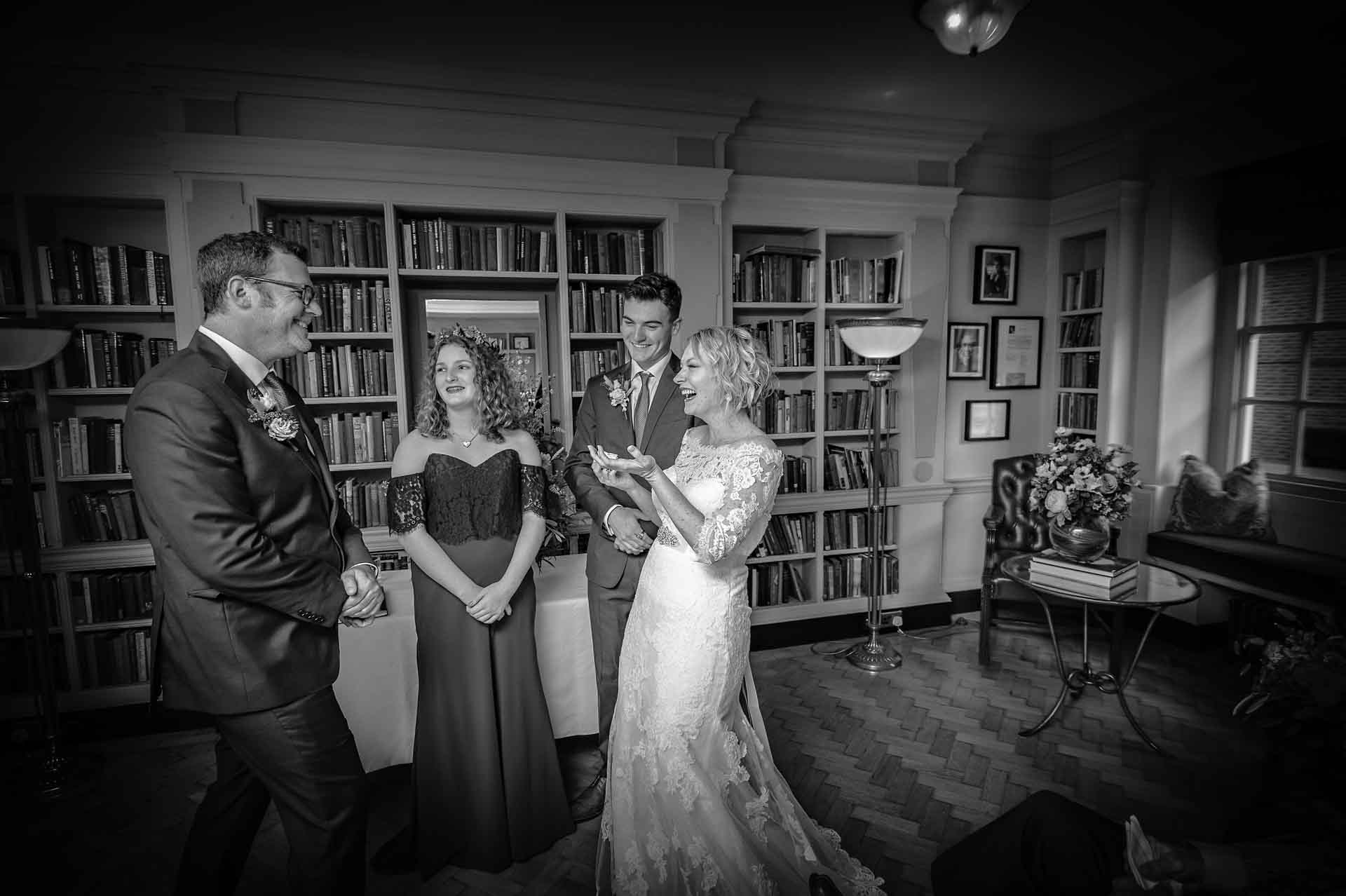 Bride and groom laughing in front of family in Seamus Heaney Library at the Bloomsbury Hotel
