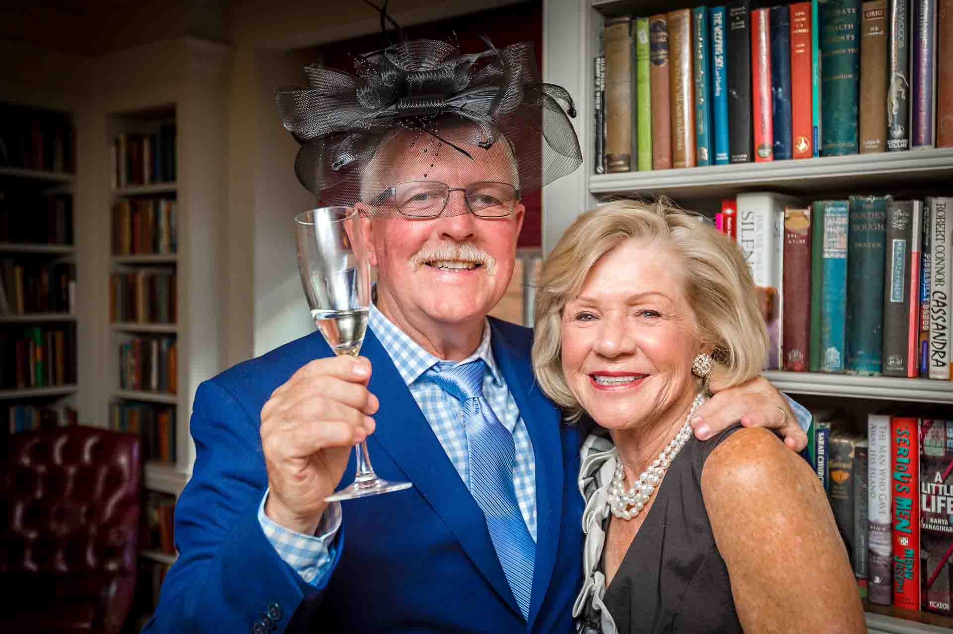 Man jokingly wearing favour and holding wine glass with wife at wedding