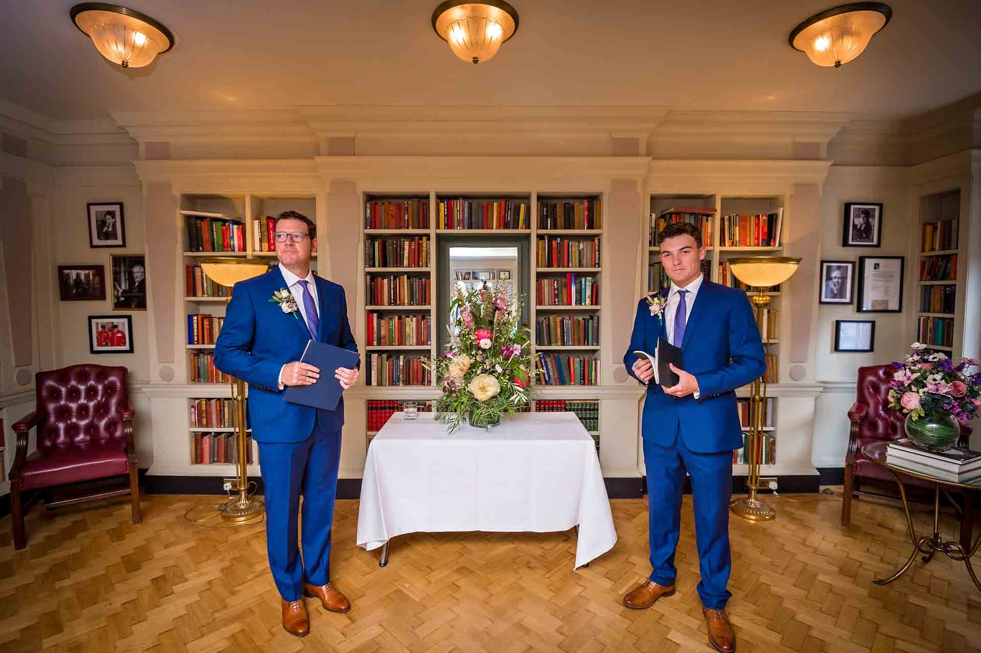 Two men in suits standing at front of Seamus Heaney Library at wedding in the Bloomsbury Hotel