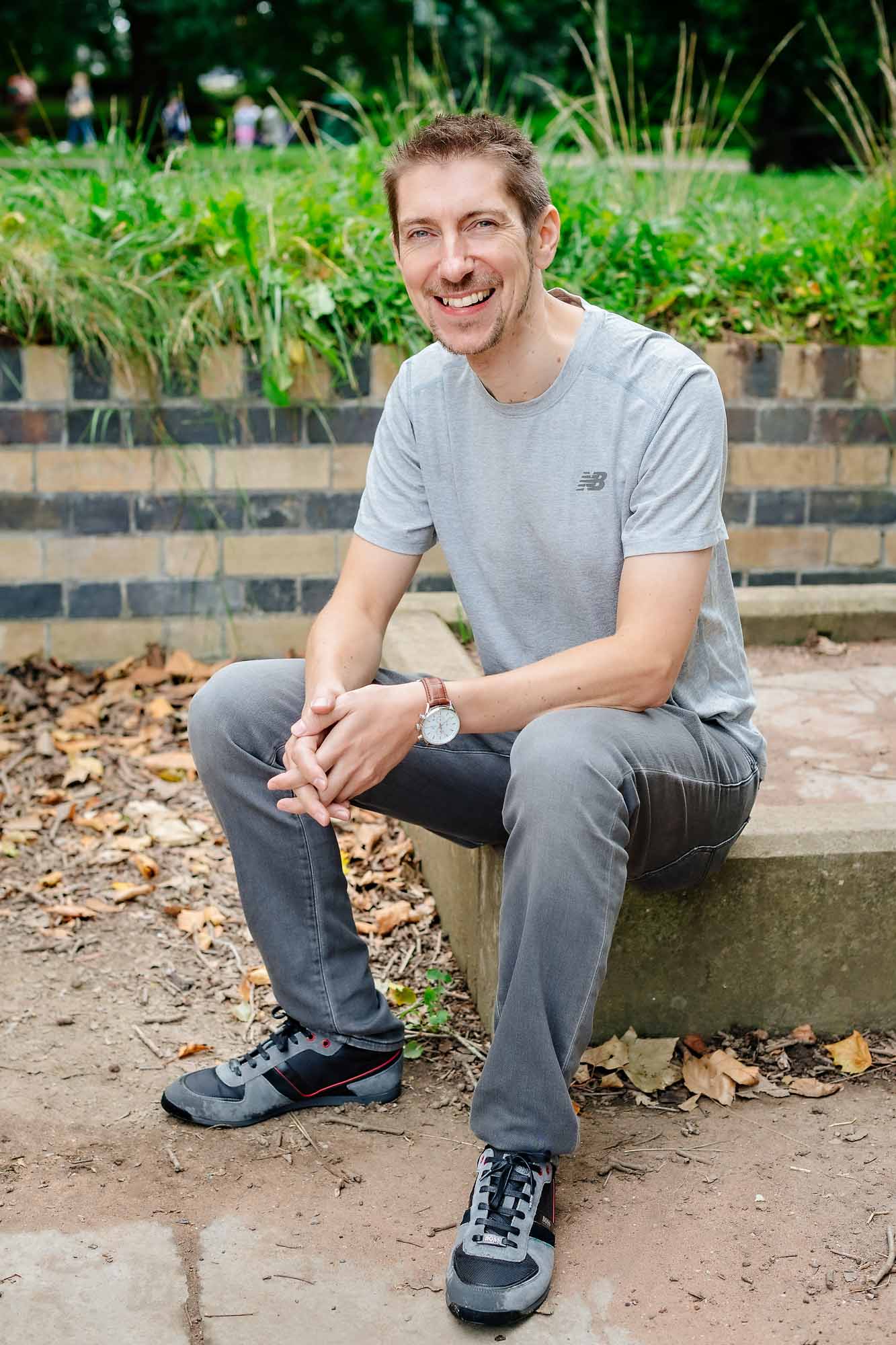 Smiling man sitting on wall and posing for dating profile photos