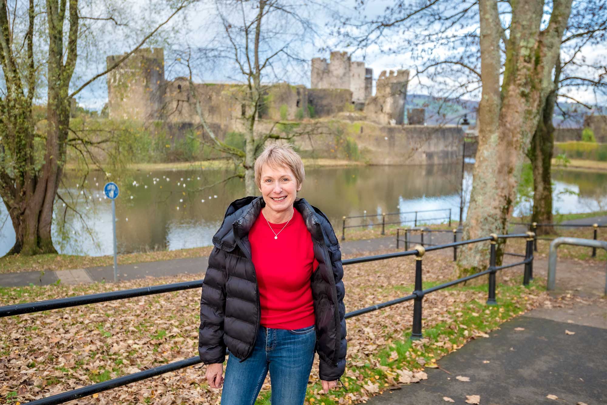 Smiling lady with Caerphilly Castle in the background in Autumn