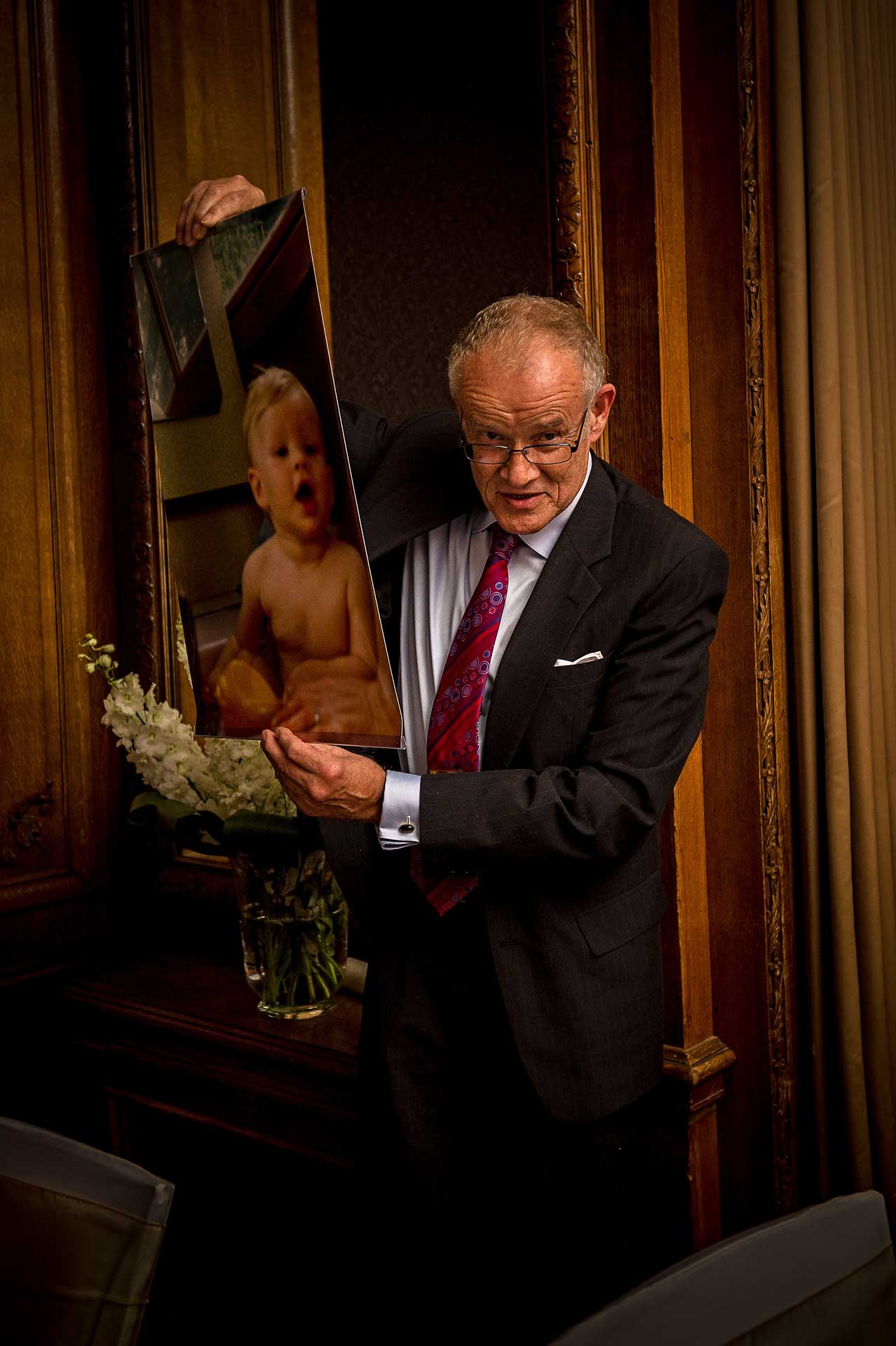 Father of the groom holding up a photo of the groom as a baby