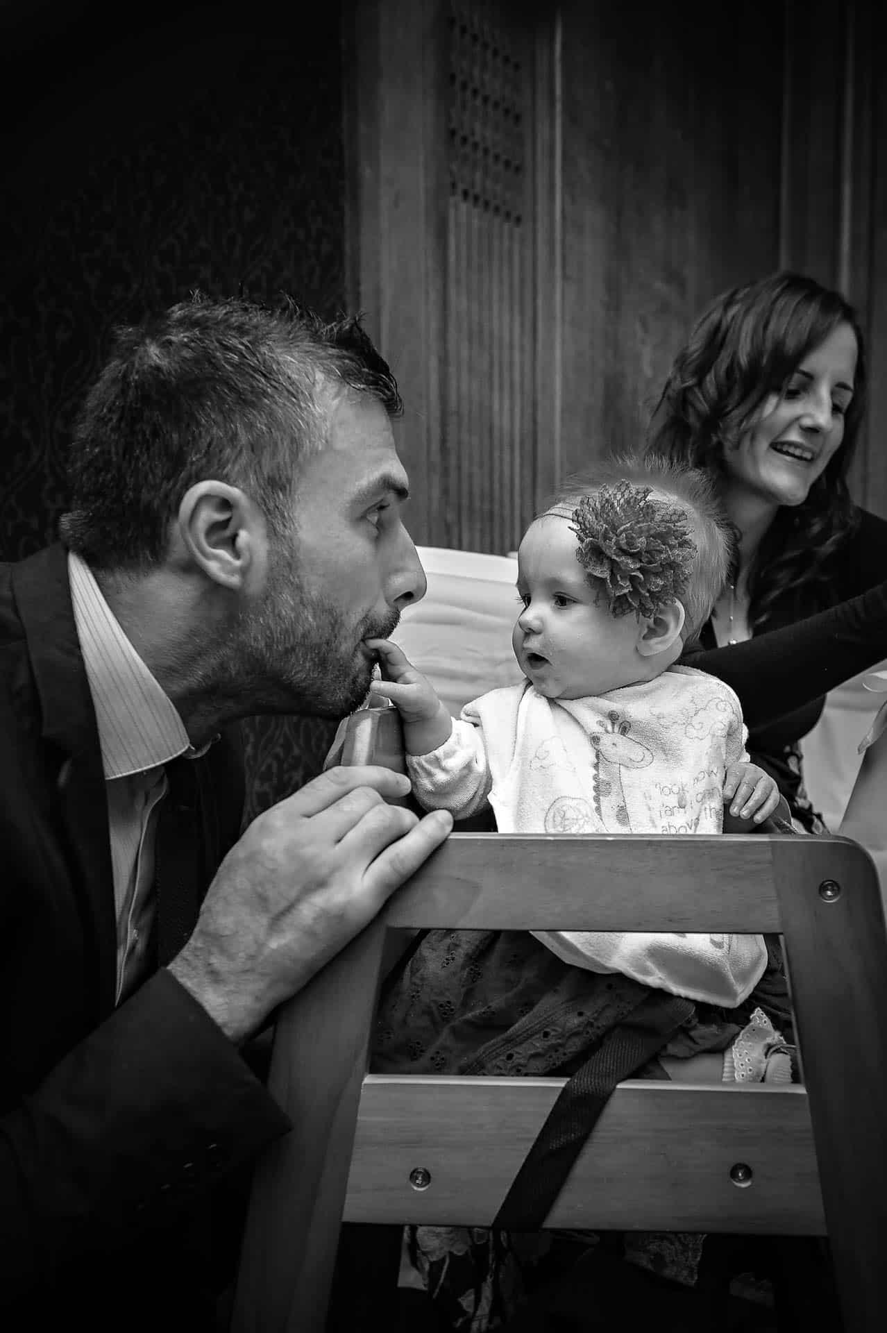 Baby with hand in man's mouth at wedding