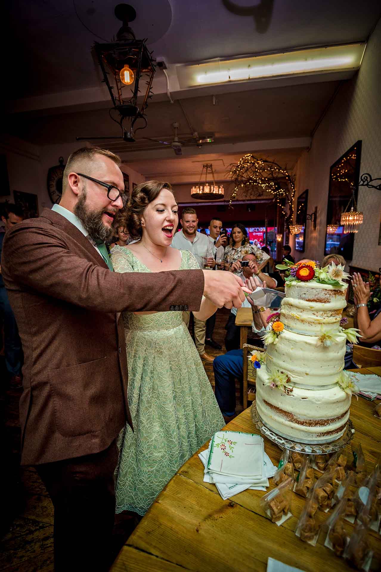Bride and Groom carefully cutting the wedding cake in London cafe