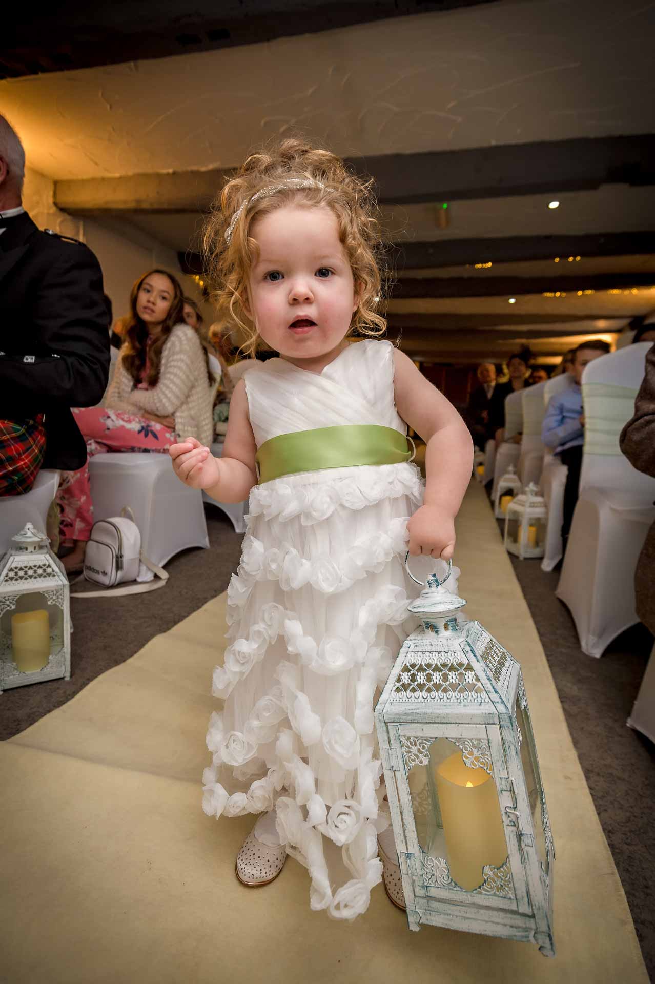 Young bridesmaid carrying candle lantern at wedding in Nelson's Llechwen Hall Hotel