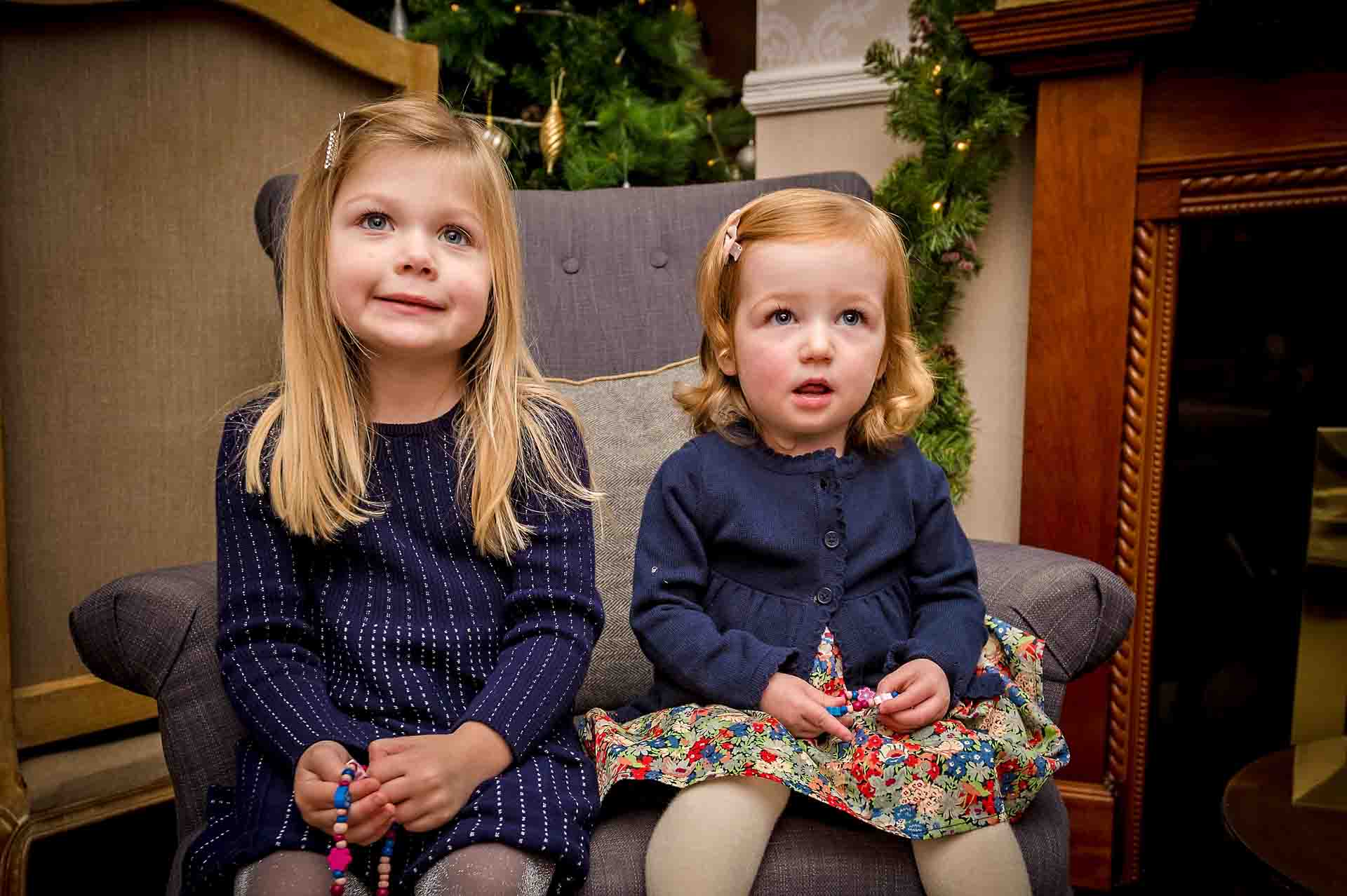 Two girls sitting on same chair in Llechwen Hall Hotel near Pontypridd