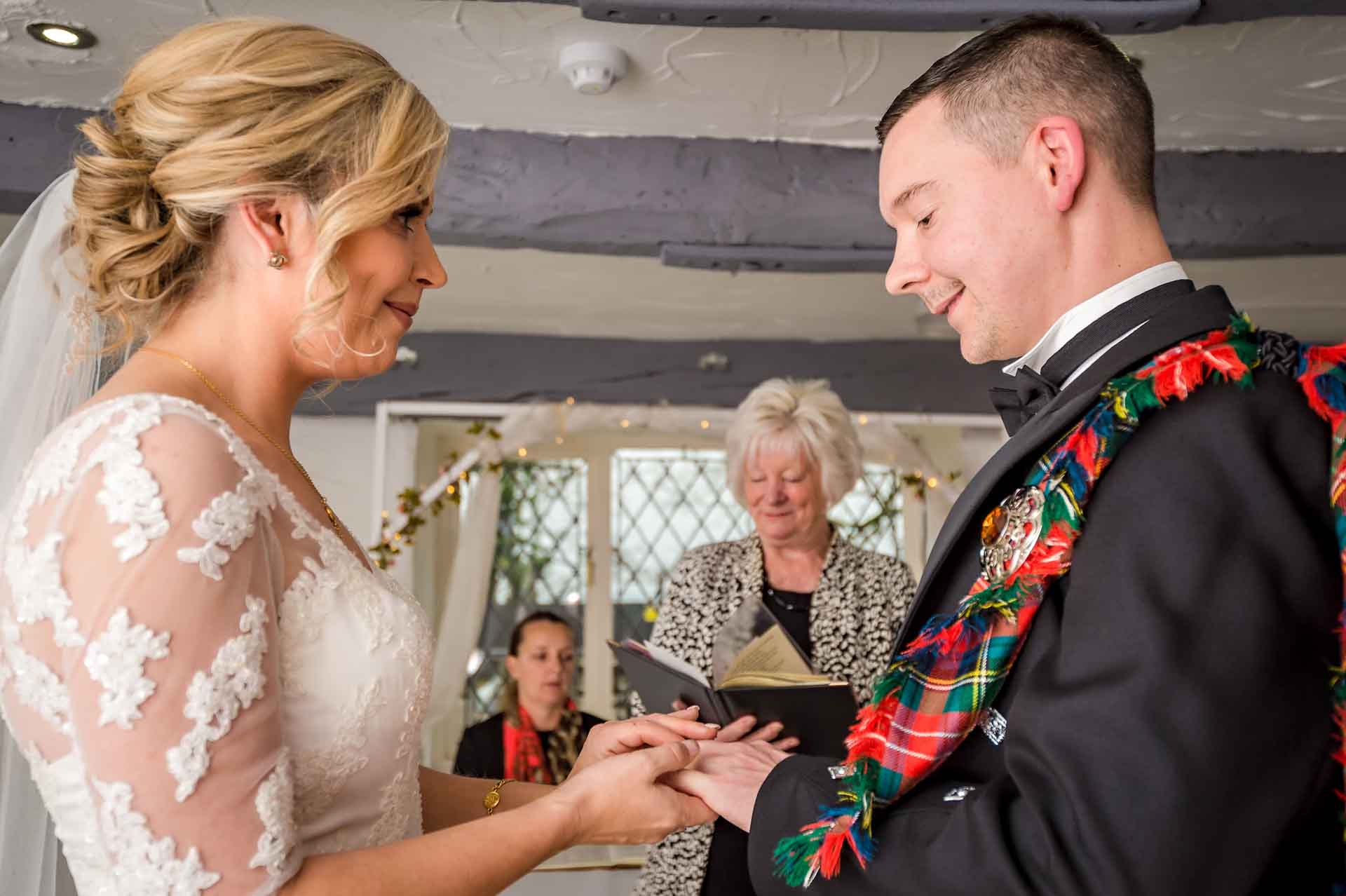 The bride places the ring on the groom's finger at Llechwen Hall Hotel wedding