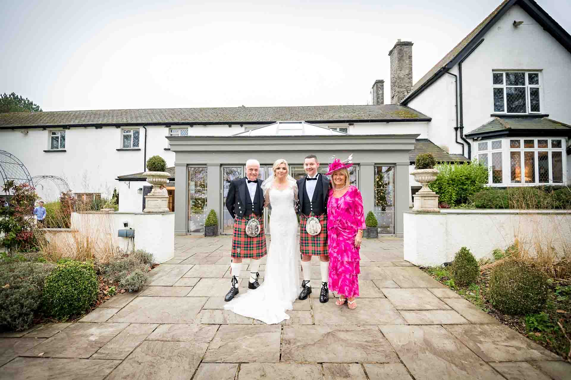 Portrait of happy couple with parents at wedding outside Llechwen Hall Hotel
