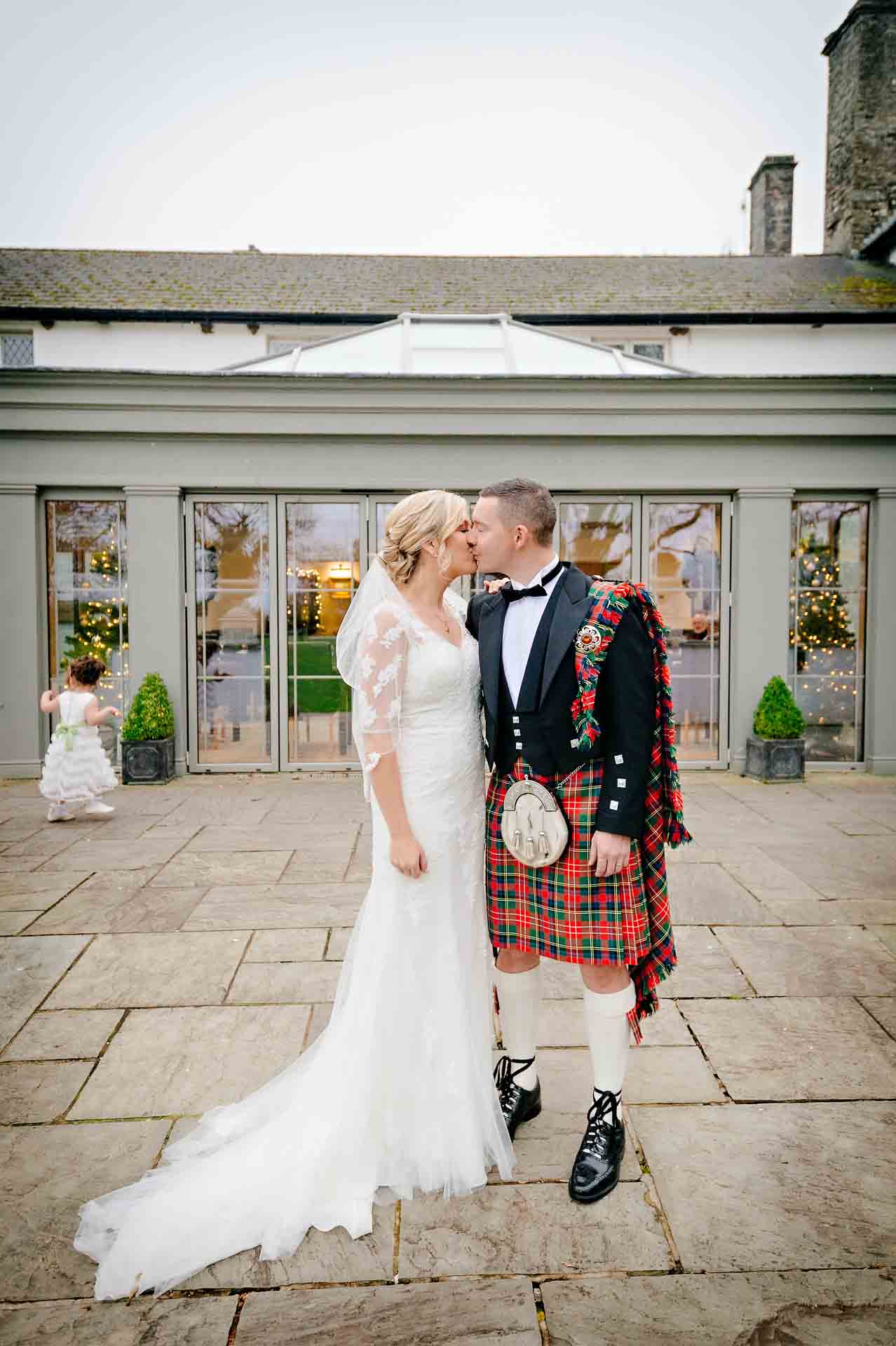 Bride and groom in kilt kiss outside Llechwen Hall Hotel