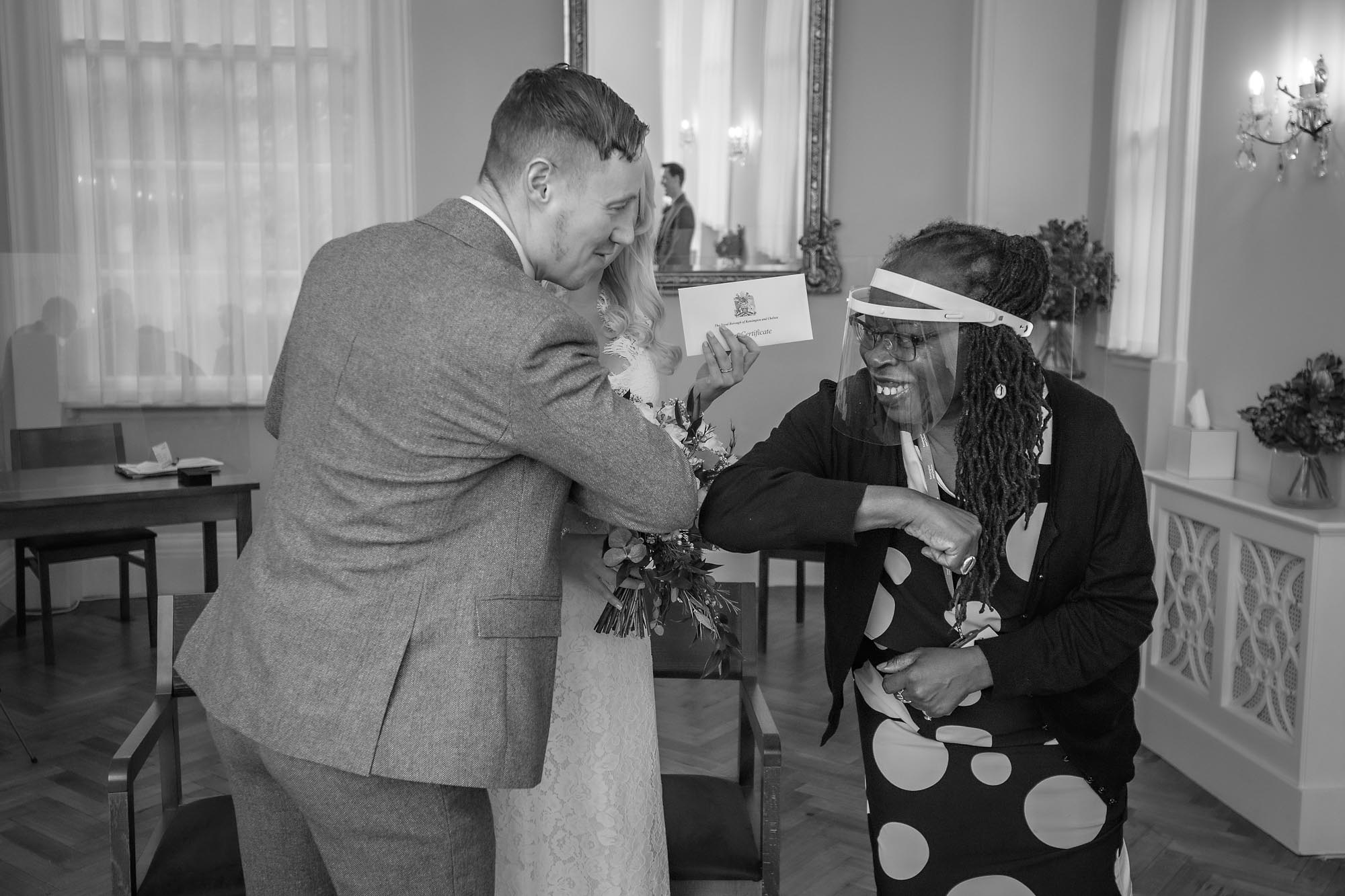 Registrar elbow bumping the groom at Chelsea Old Town Hall shortly after the Coronavirus lockdown restrictions had eased.