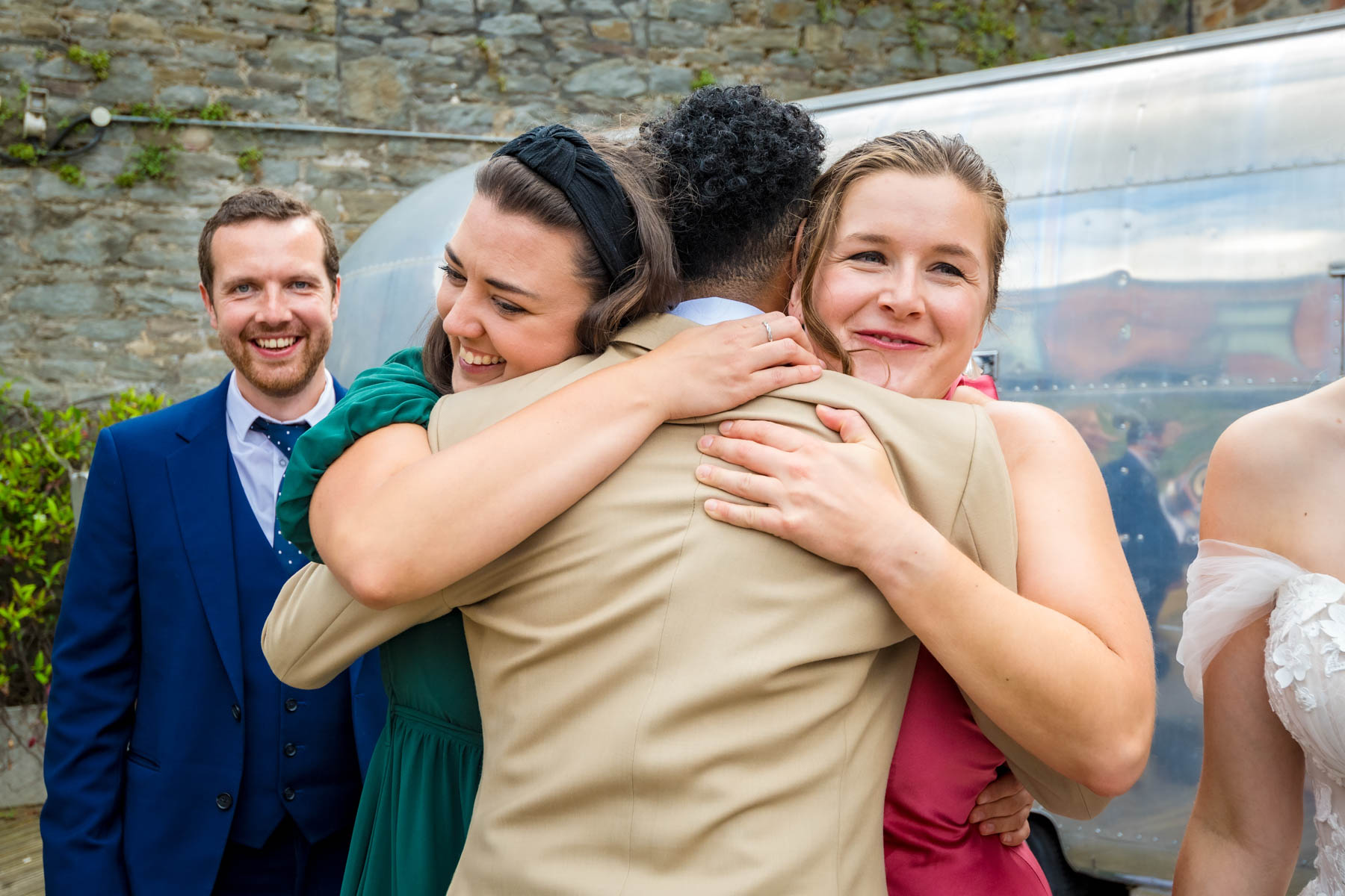Groom being hugged by two female guests at wedding