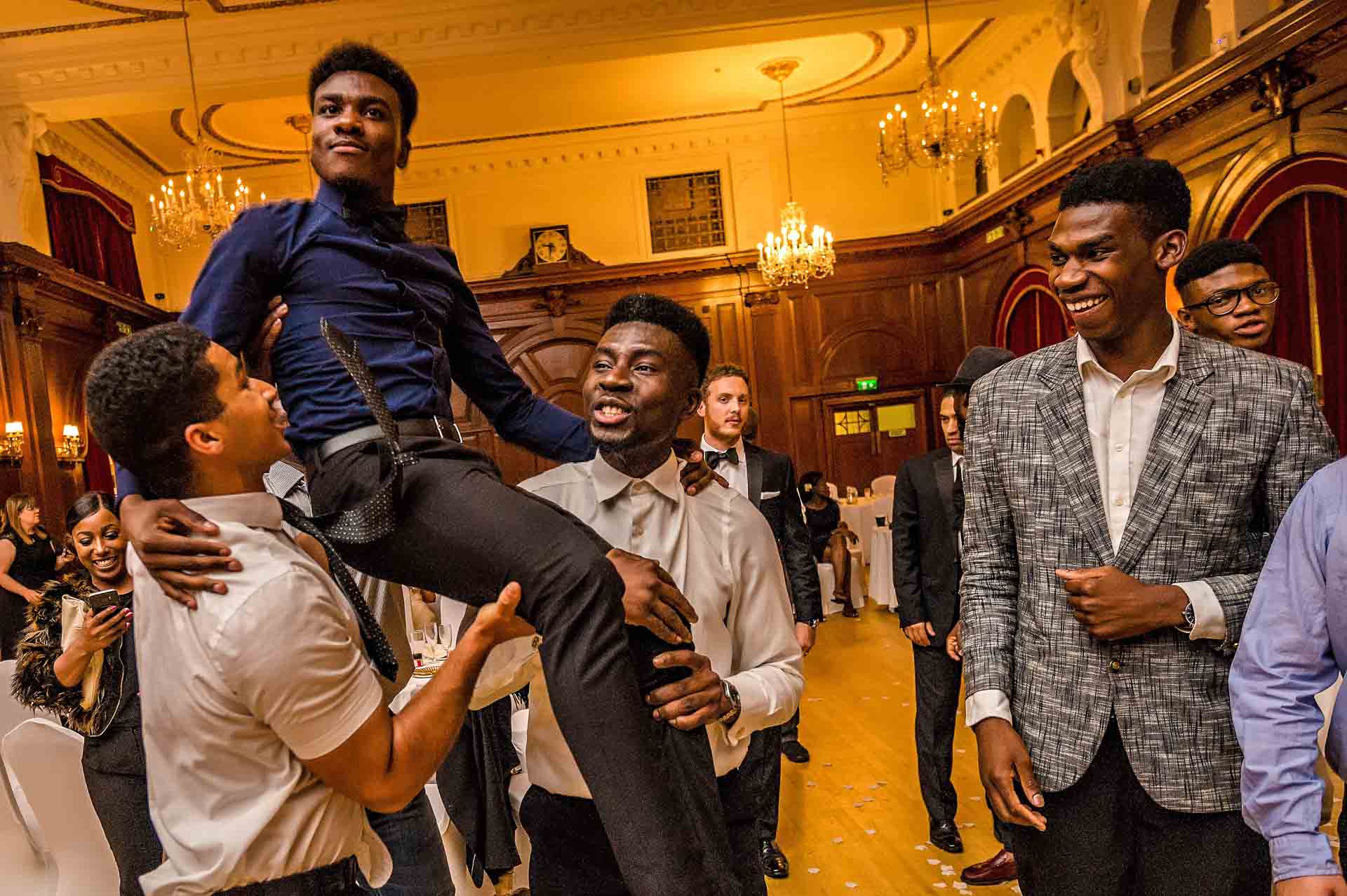 Men lifting up friend at wedding celebration
