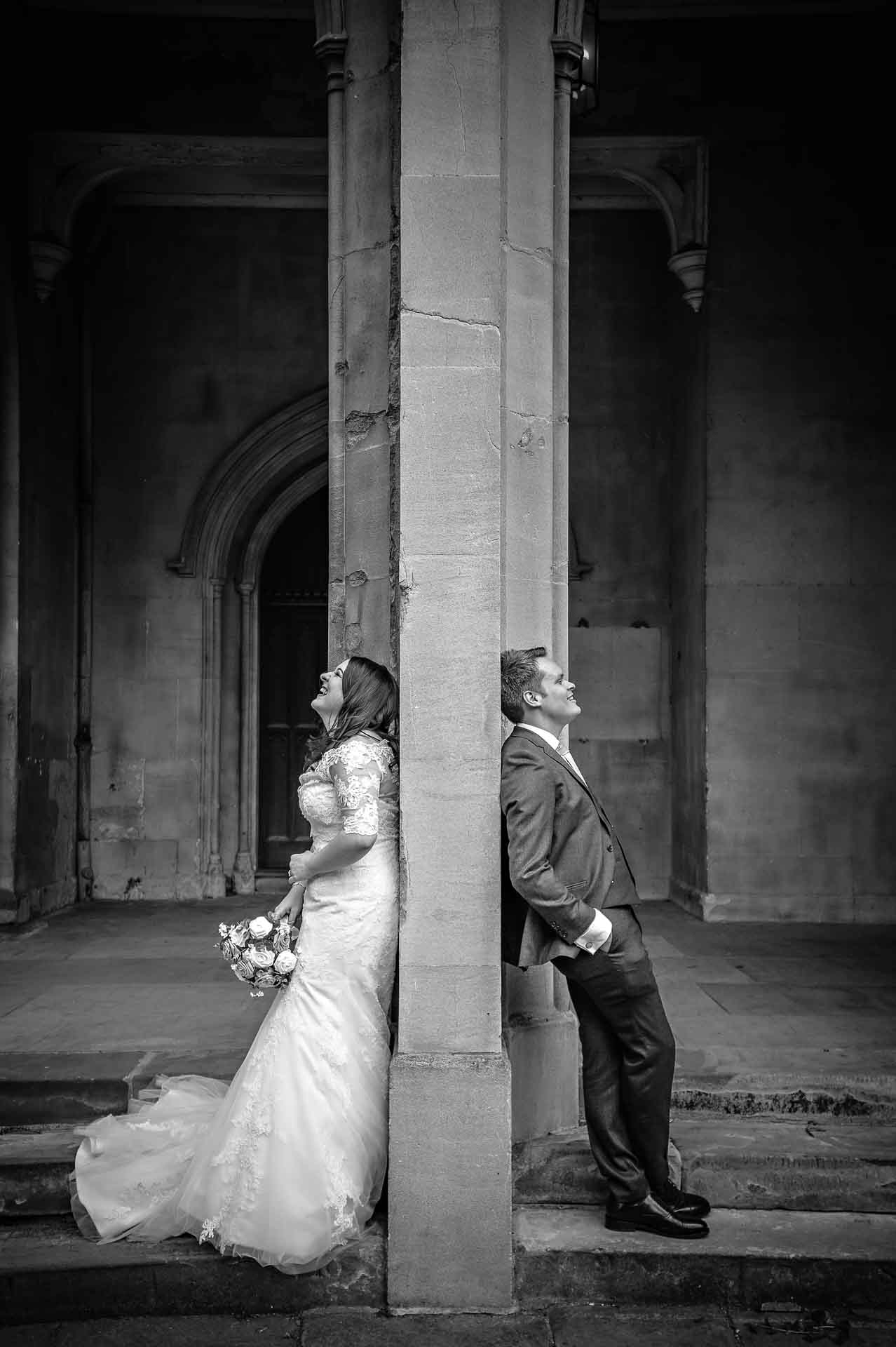 Black and white portrait of married couple back to back either side of a church wall