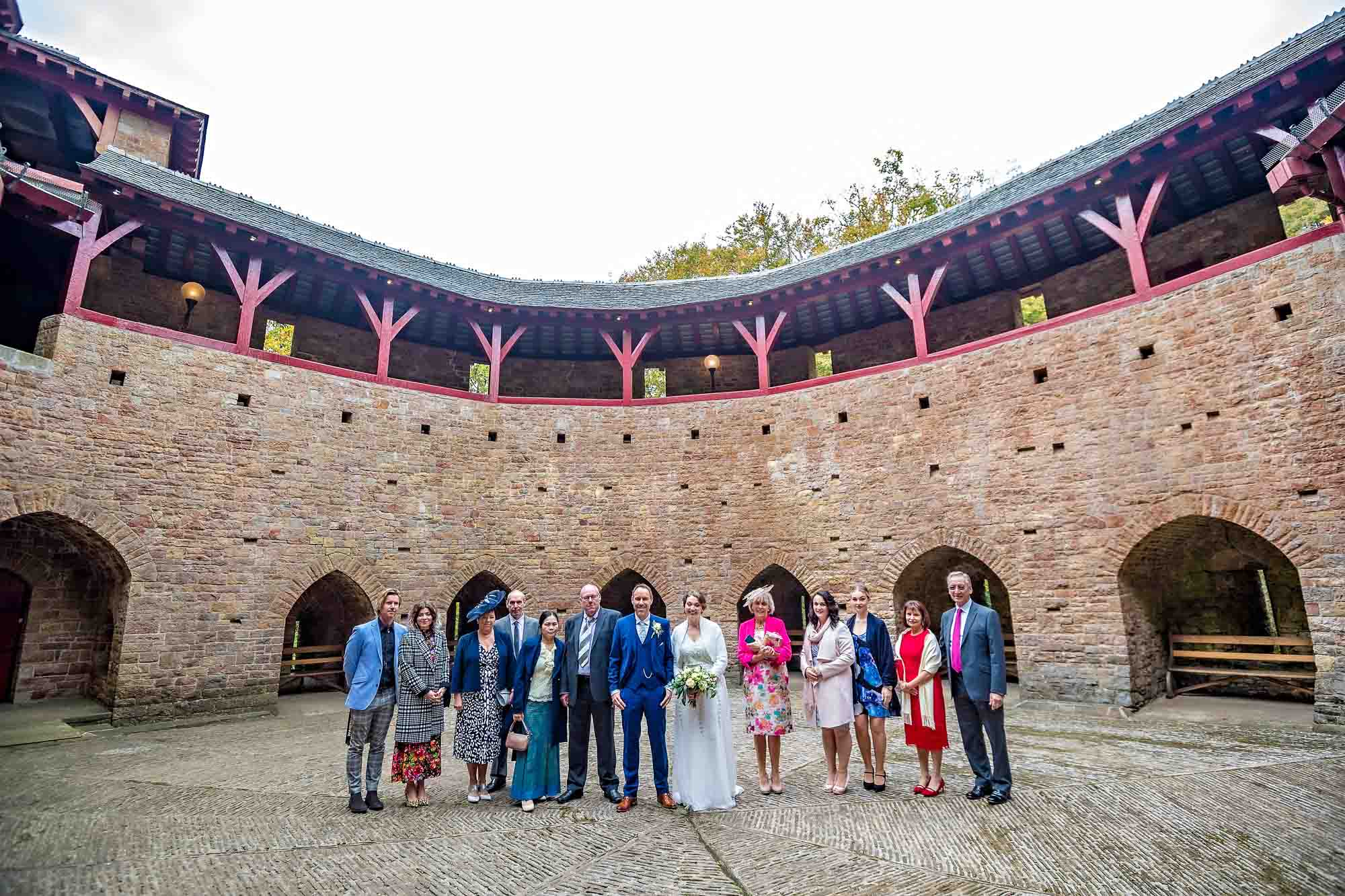 Whole wedding party lined up for photo in the courtyard of Castell Coch