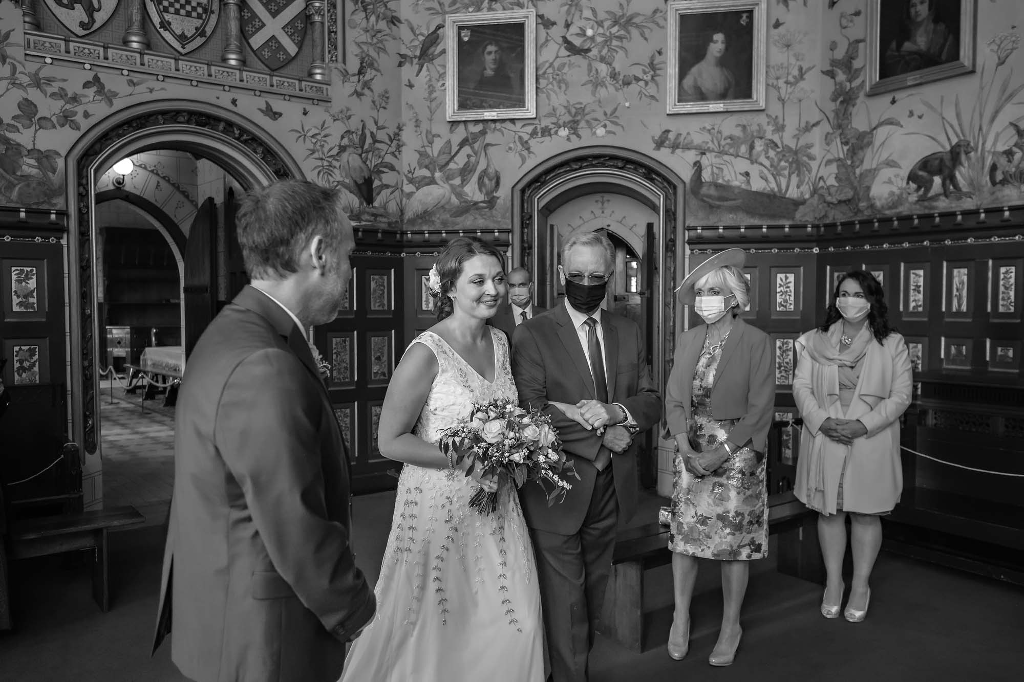 Masked guests watch the bride as she enters her wedding at Castell Coch