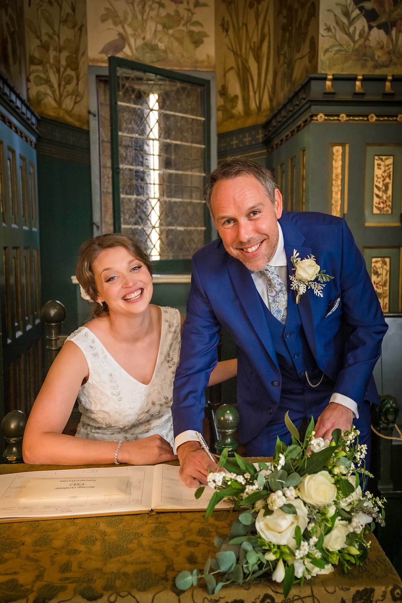 The bride and groom pose with the register in the drawing room at Castell Coch