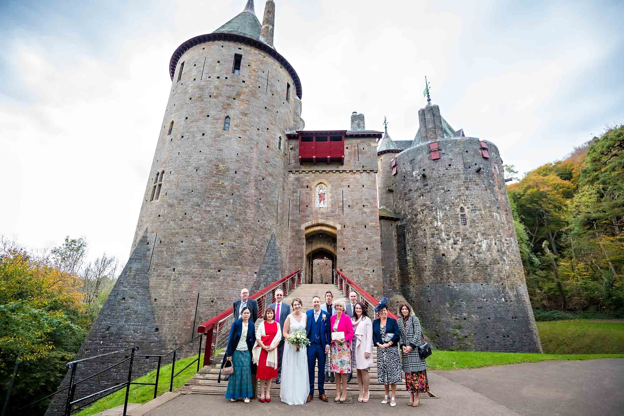 Wedding party posing outside Castell Coch, with the whole of the venue in the background