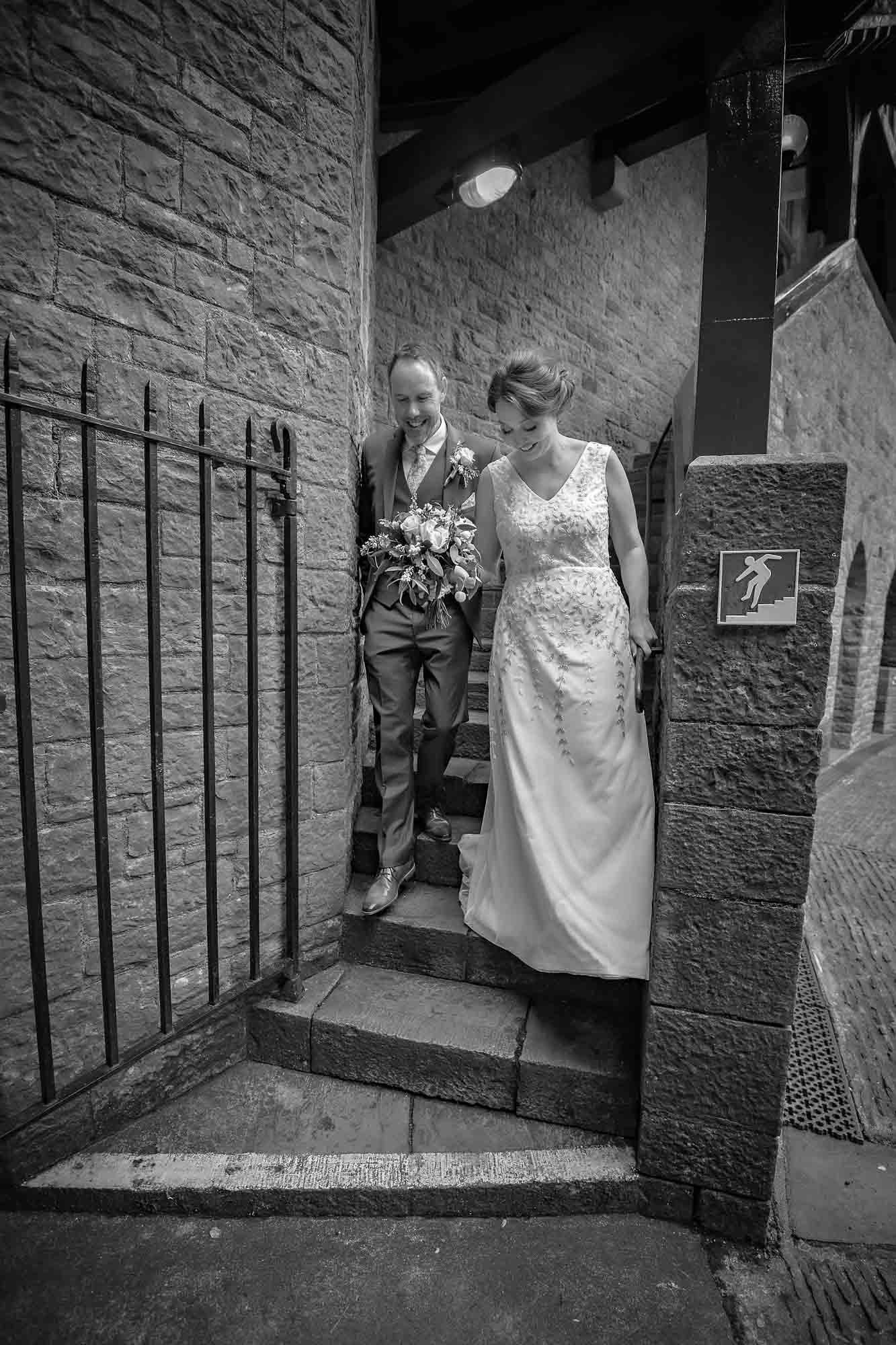 The couple walk down the steps into the courtyard at their Castell Coch wedding