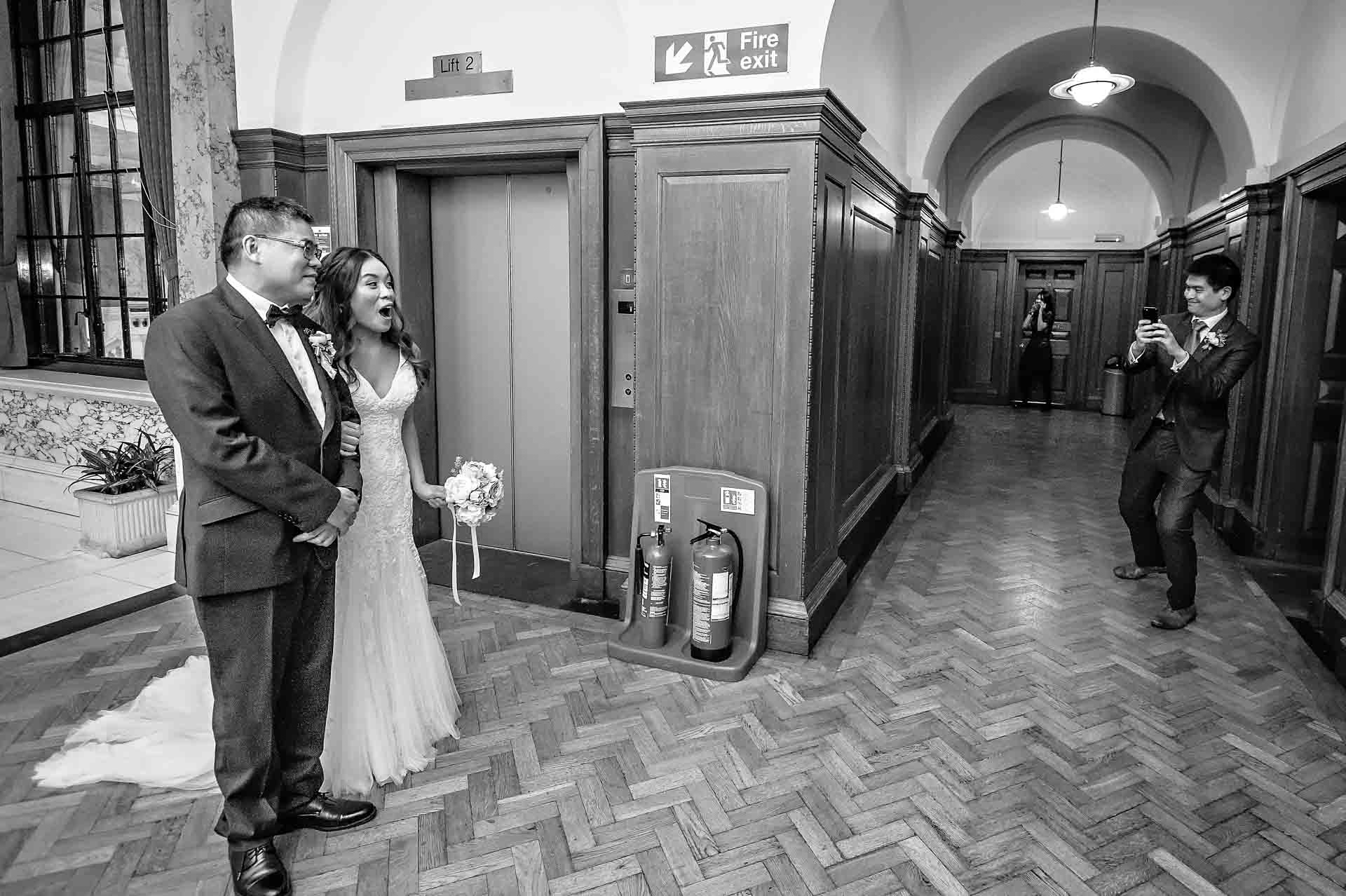Bride surprised as guests photographs her on phone at Camden Town Hall.