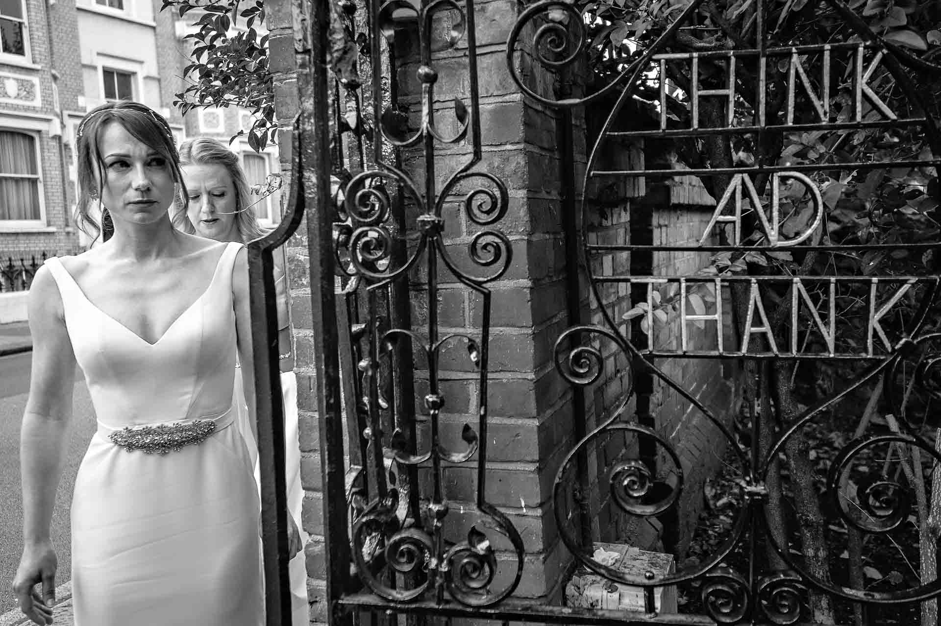 Bride by gate looking into garden with 'Think and Thank' sign on gate - Winchester House Wedding Photography