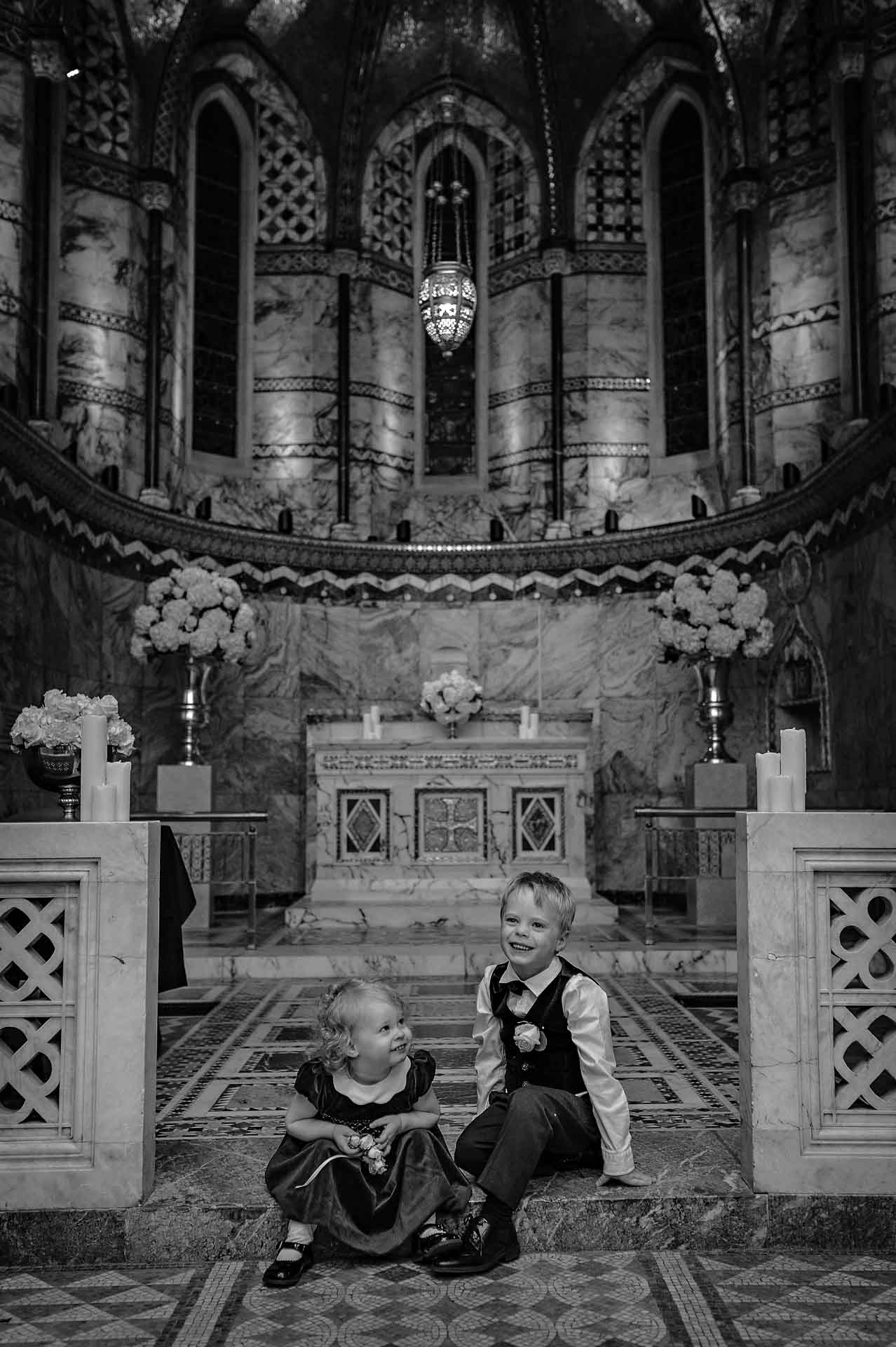 Two children having fun sitting down at the front of Fitzrovia Chapel