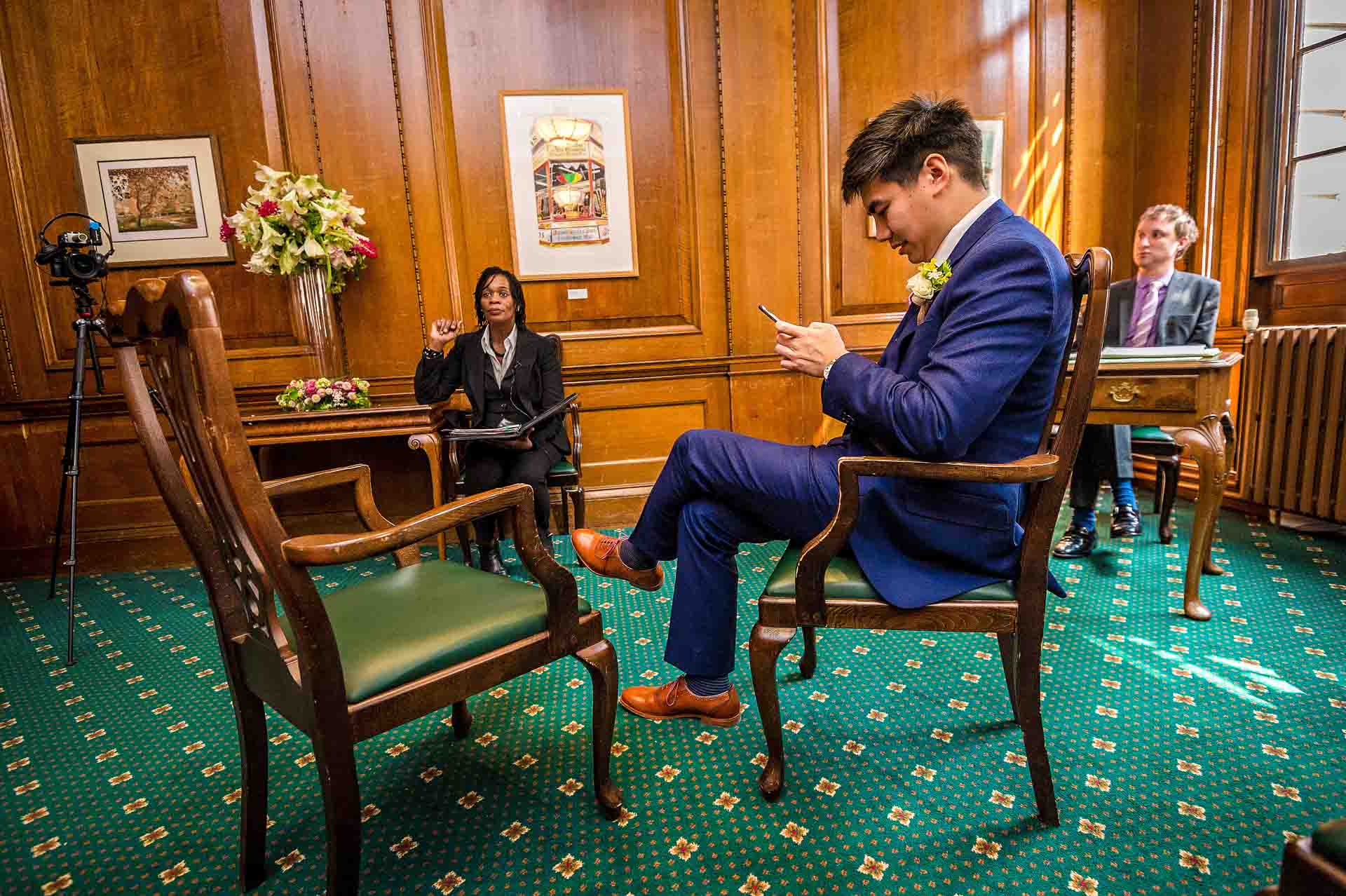 Groom sitting down on phone at register office in London