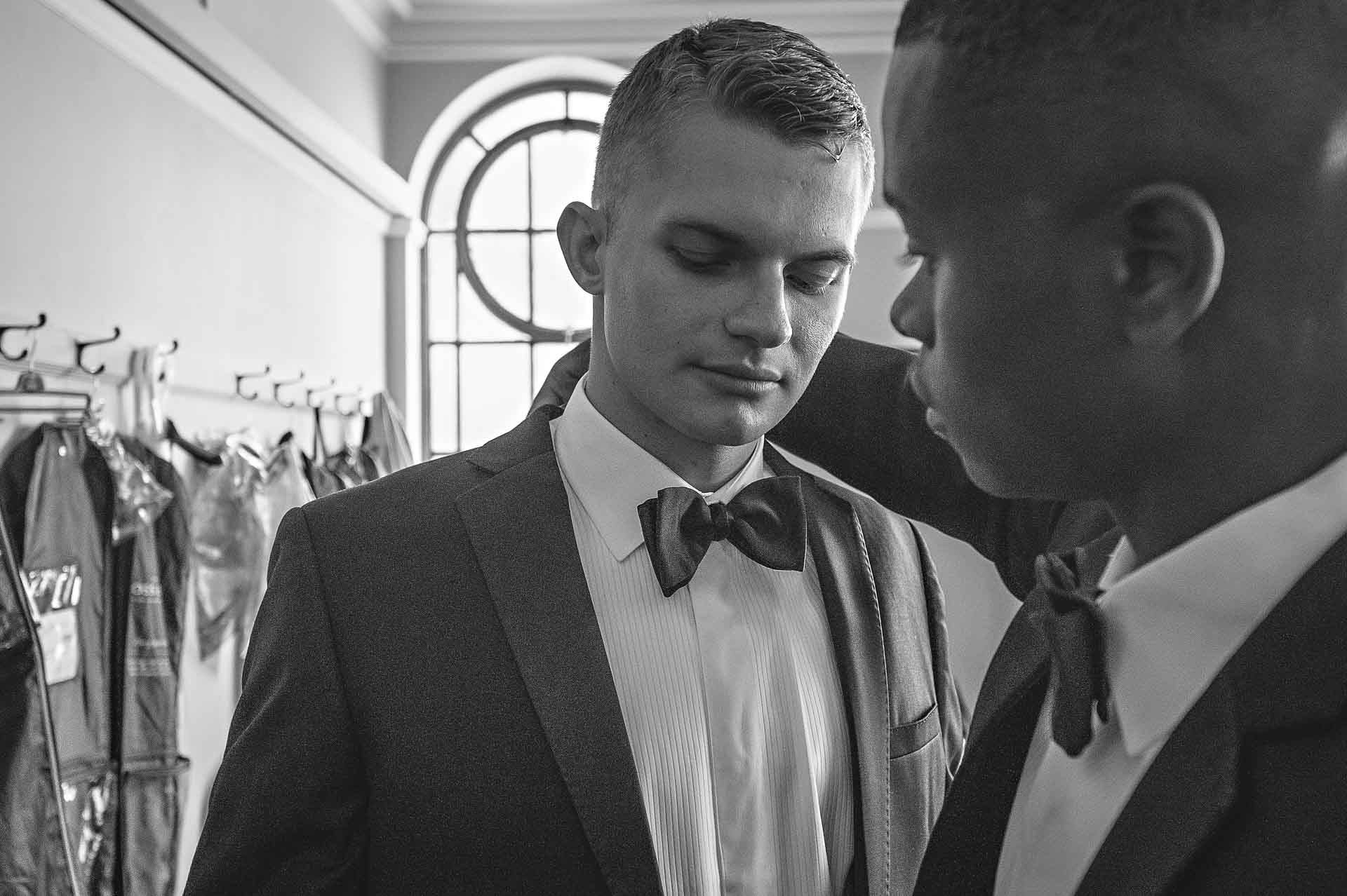 Groomsman straightening groom's collar as groom looks nervous - London Wedding Photography