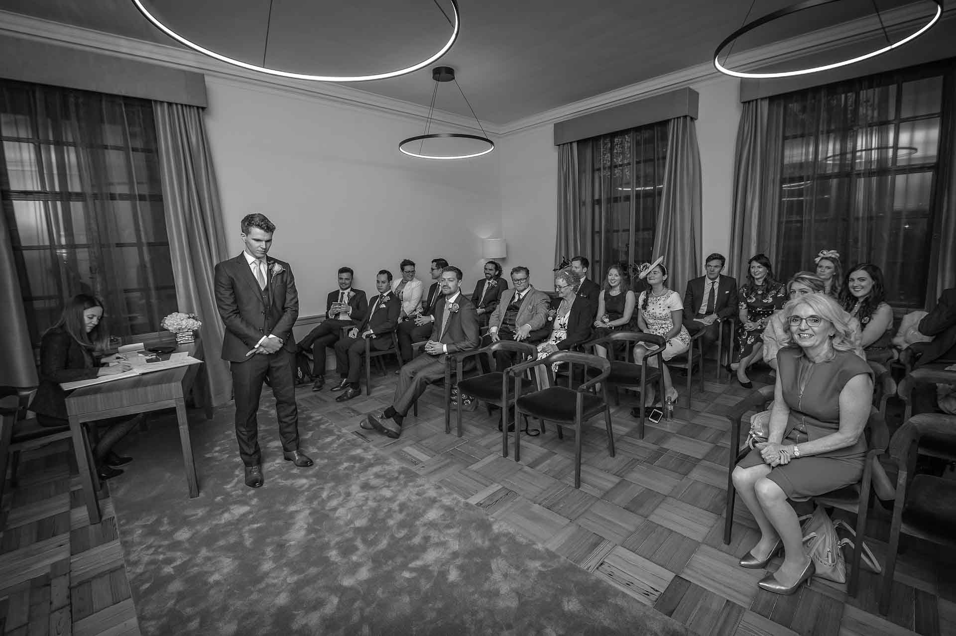 Grooms standing with seated guests at Old Marylebone Town Hall Wedding