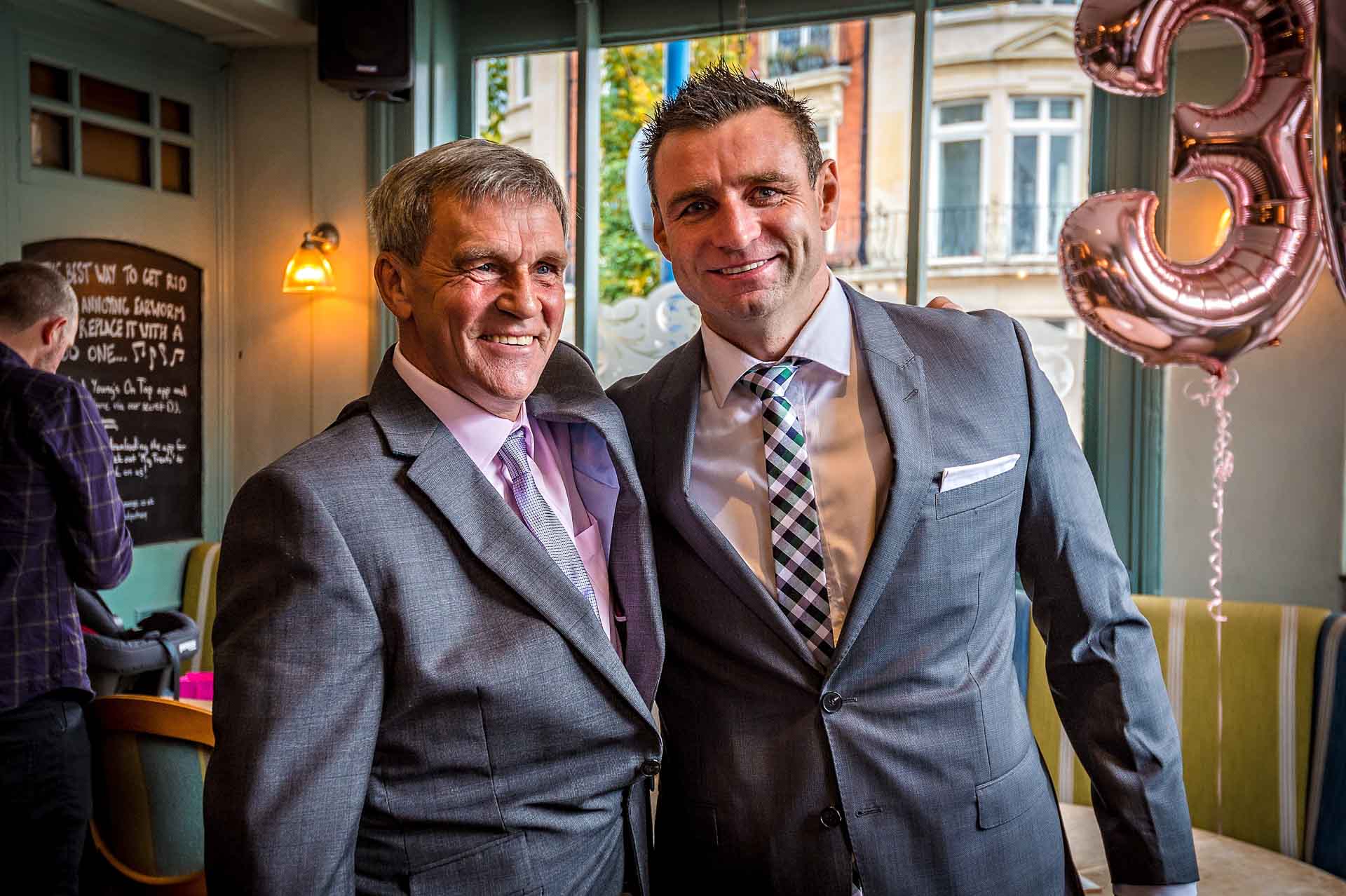 Two men smiling with each other at pub wedding in london