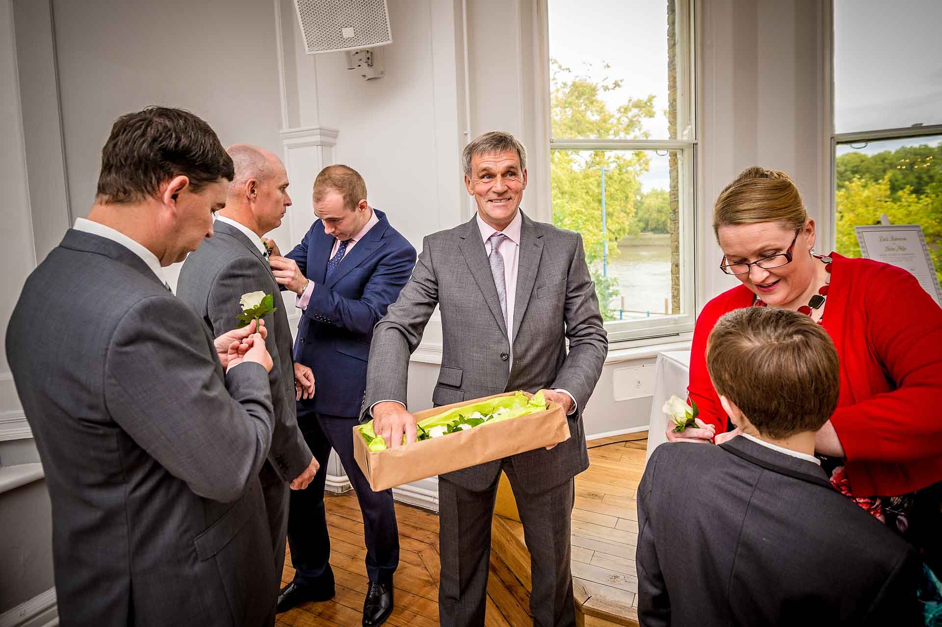 Man in suit handing out wedding button-holes and guests putting them on