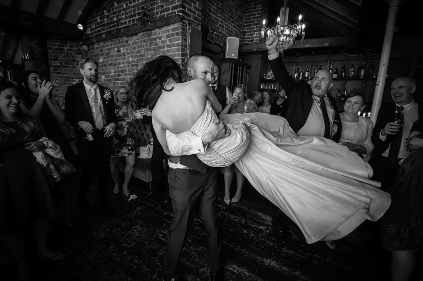 Groom lifting bride during dancing at wedding