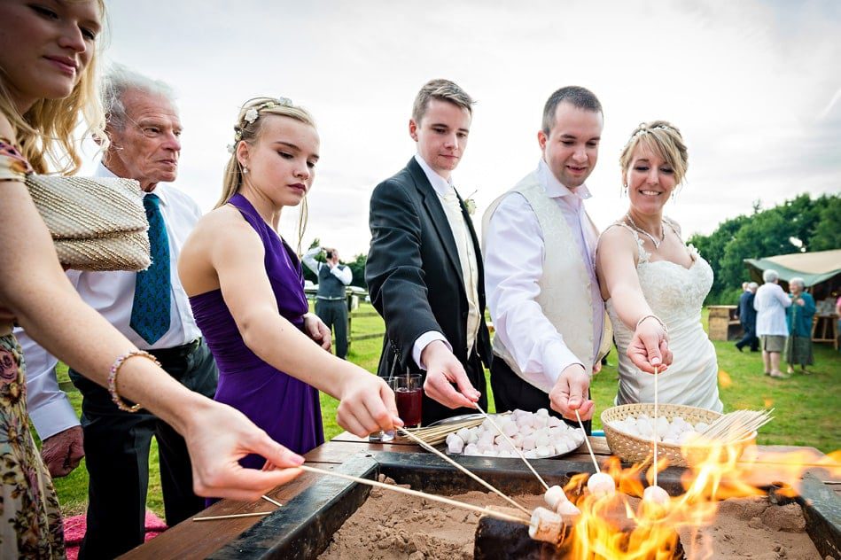 Guests and couple toast marshmallows at wedding