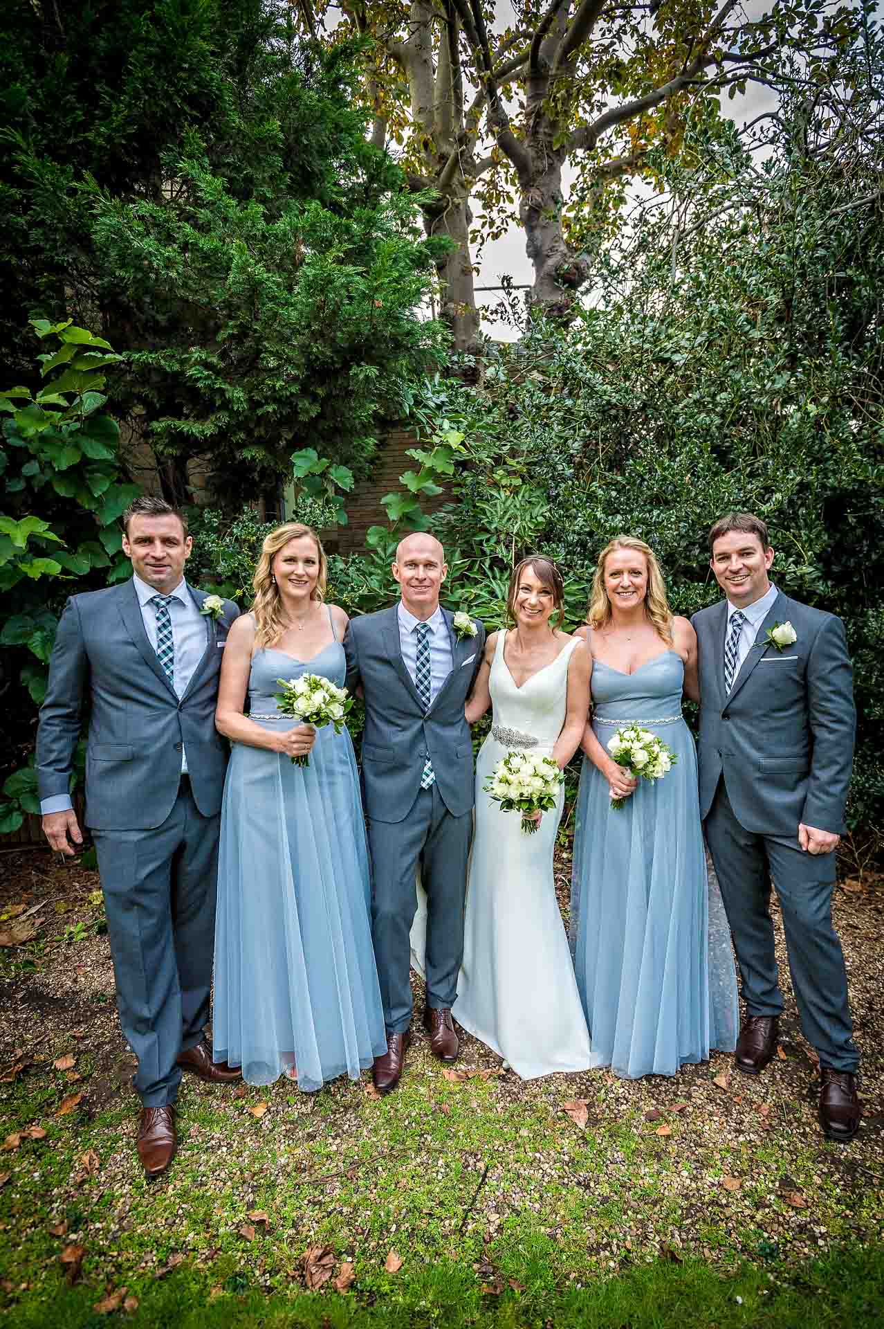 Group wedding photo with bridesmaids and groomsmen in garden