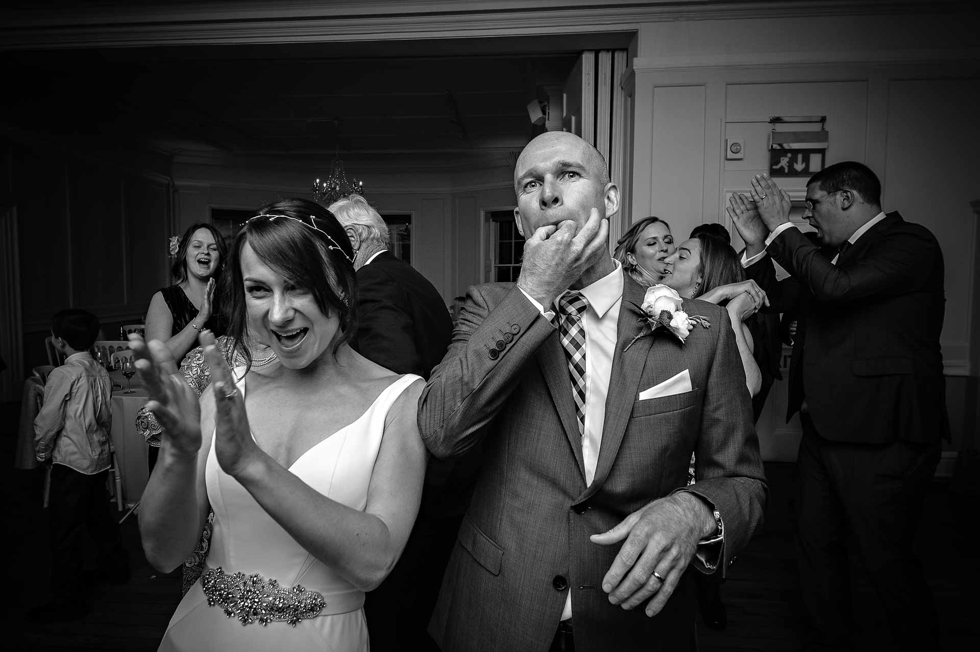 Groom whistling whilst bride claps at wedding in Winchester House, London