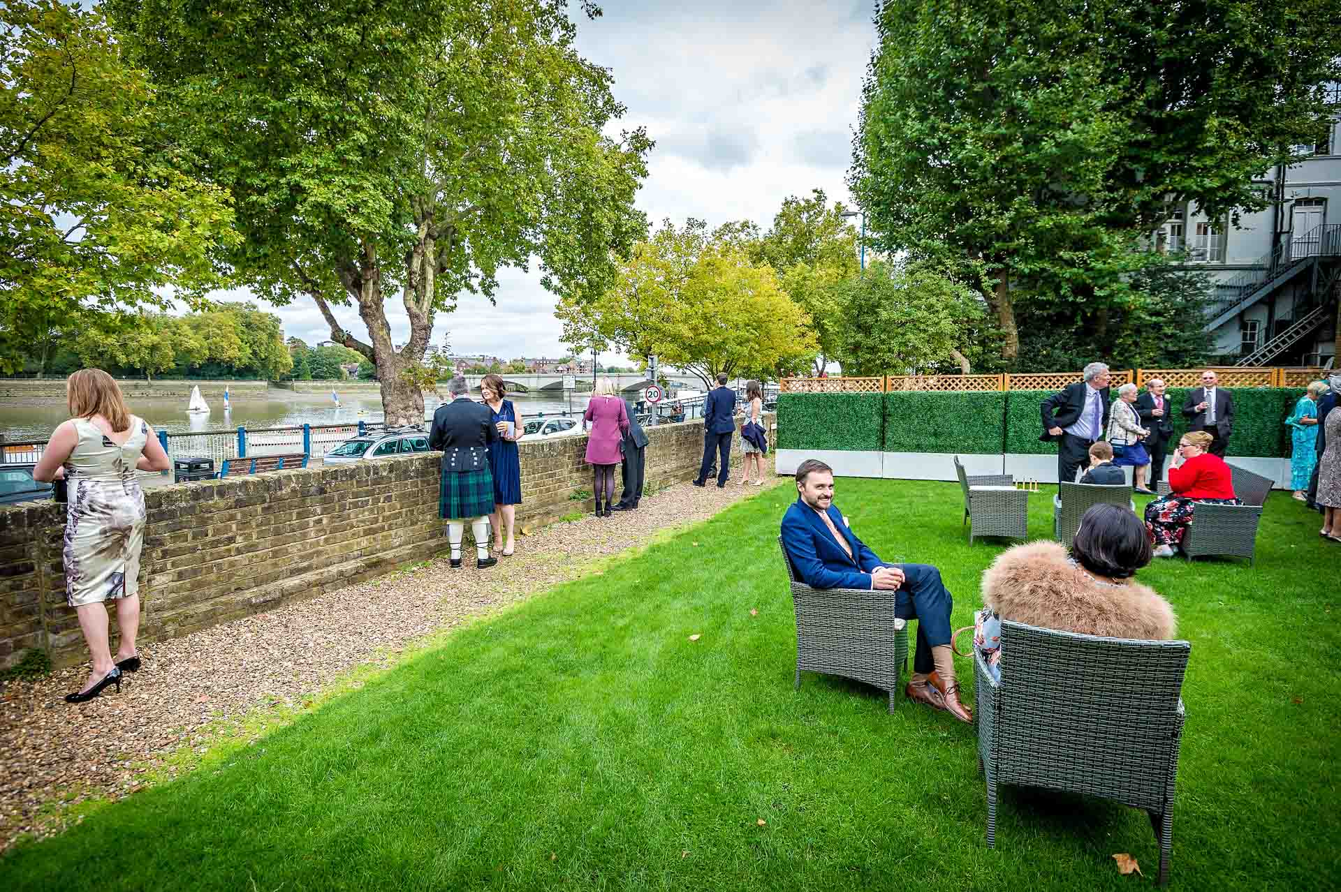 Wedding guests sitting in garden at Winchester House looking out over the Thames