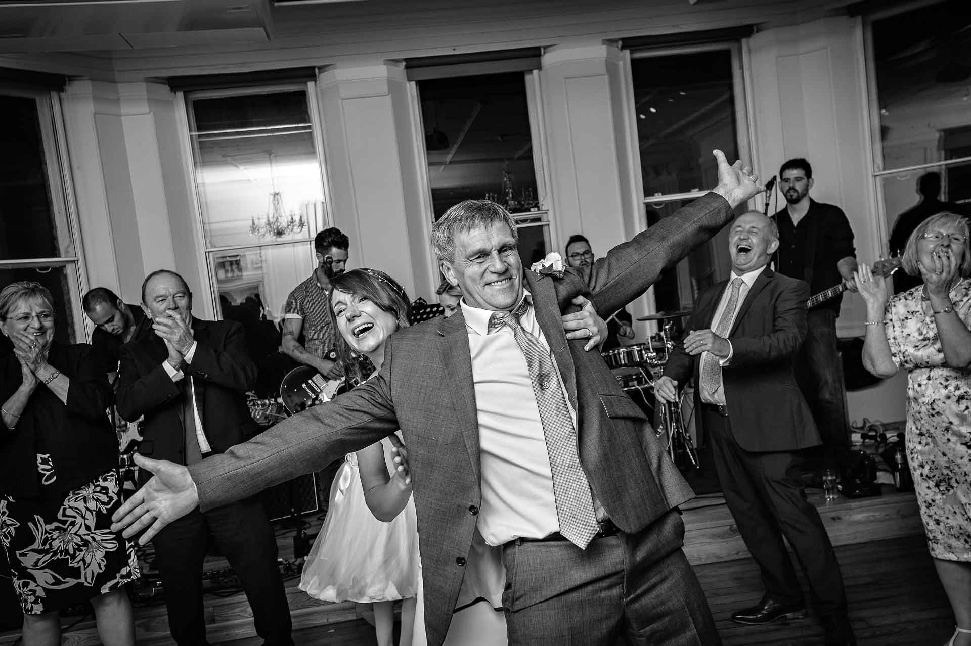 Man with arms out and bride behind at wedding in London