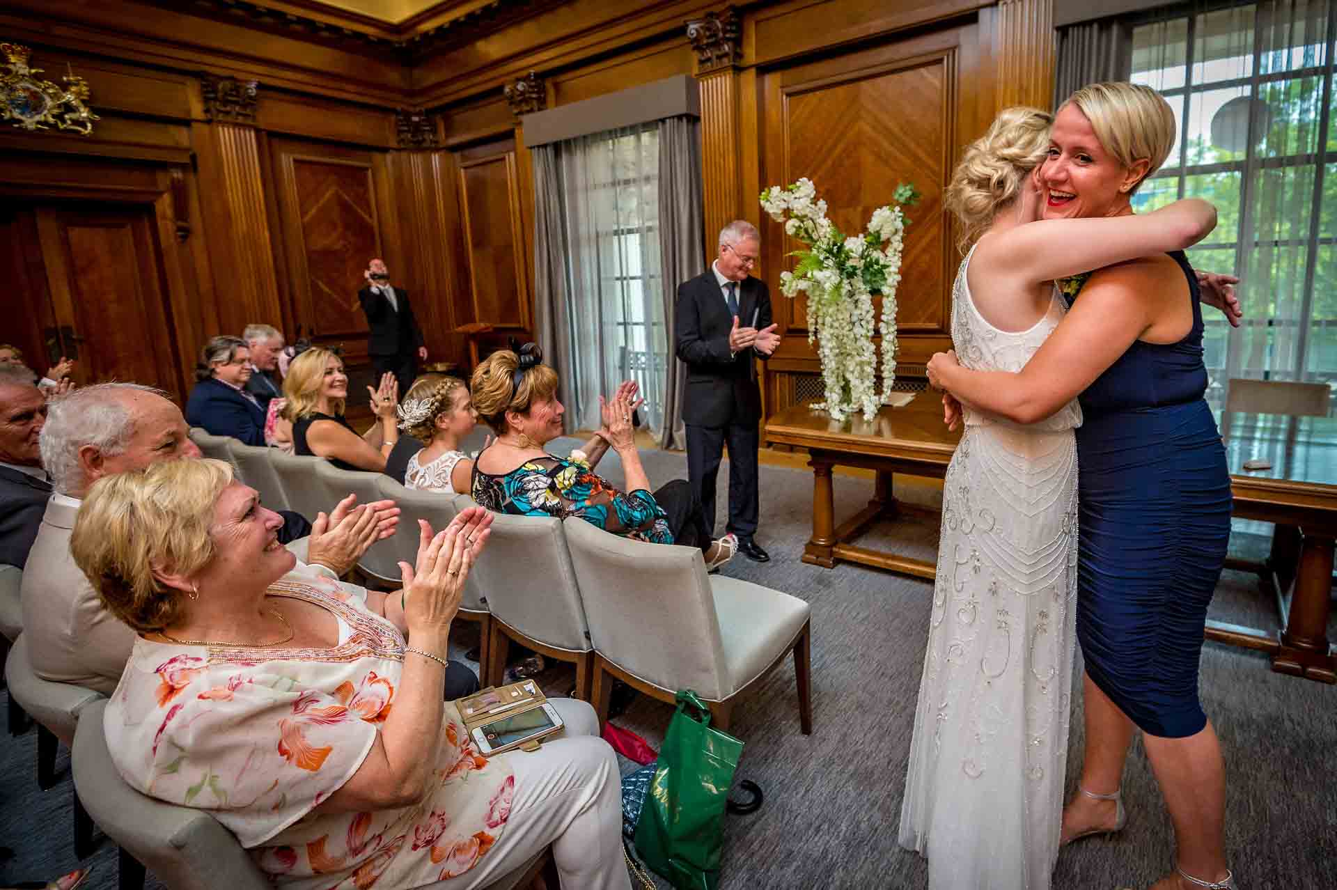 Same-sex wedding brides hugging in ceremony room