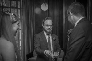 A bearded guest presents the ring to the groom at a London Wedding