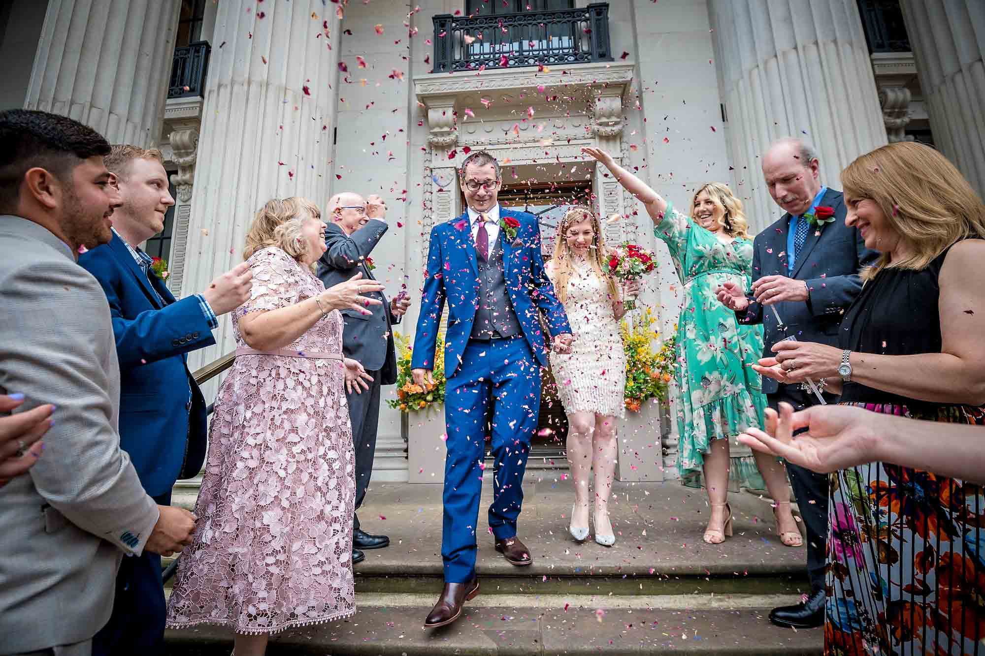 The newlyweds walking down the Old Marylebone Town Hall steps as guests throw confetti