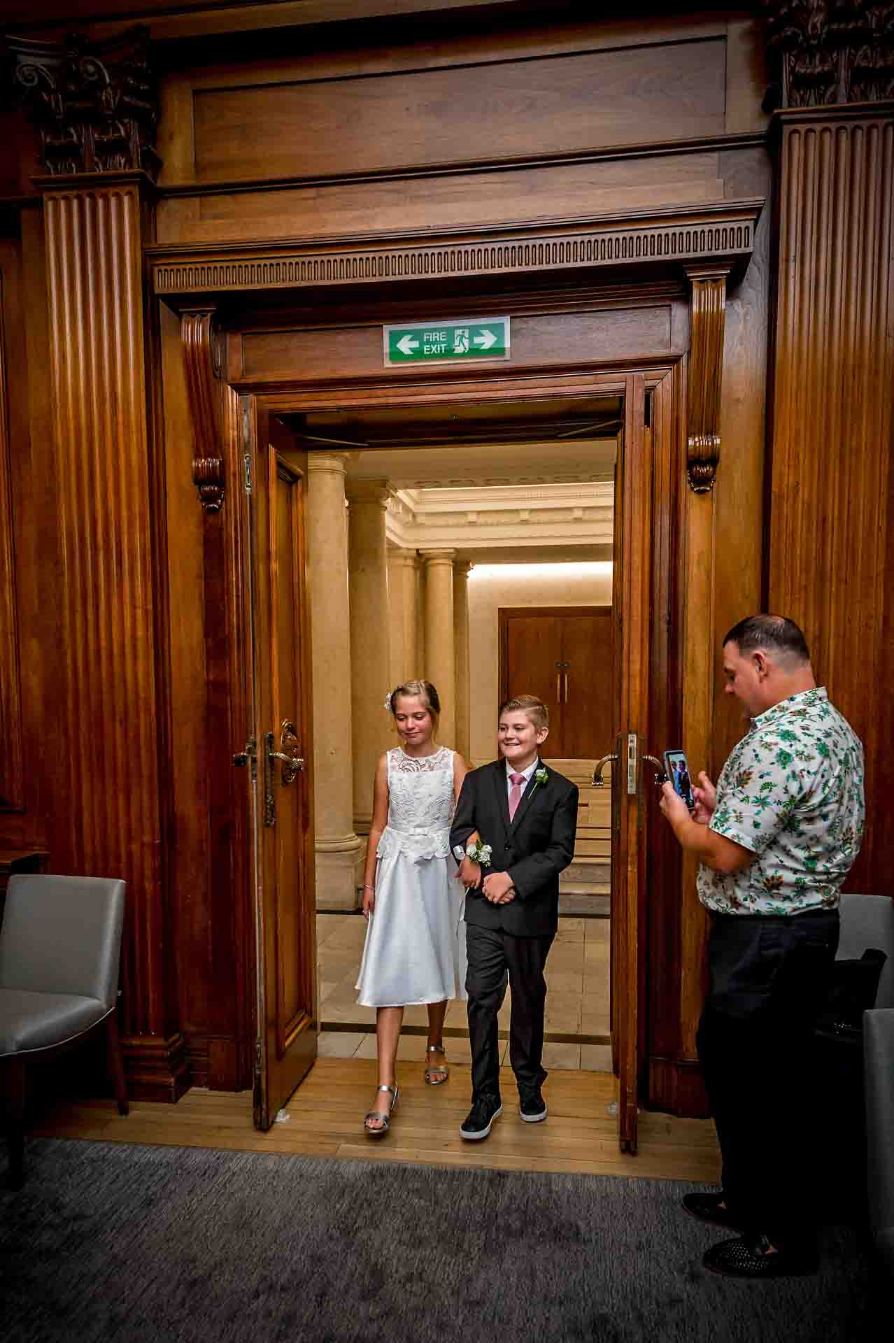 A page boy and bridesmaid entering the Westminster Room at Old Marylebone Town Hall