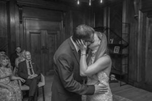 The bride holds her groom&#039;s face during their passionate first kiss at Old Marylebone Town Hall