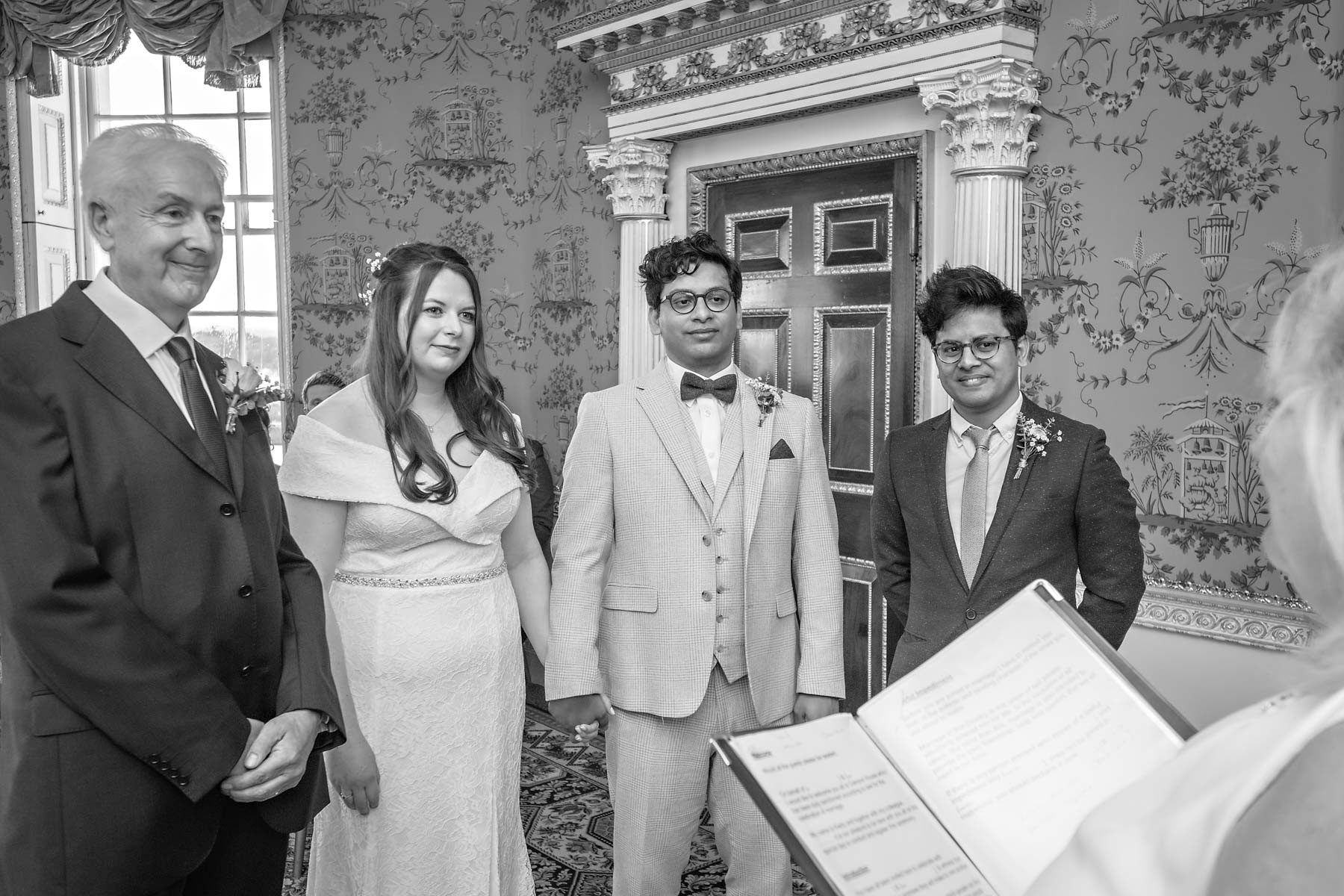 Bride and groom waiting listening to the registrar with two close family members either side.