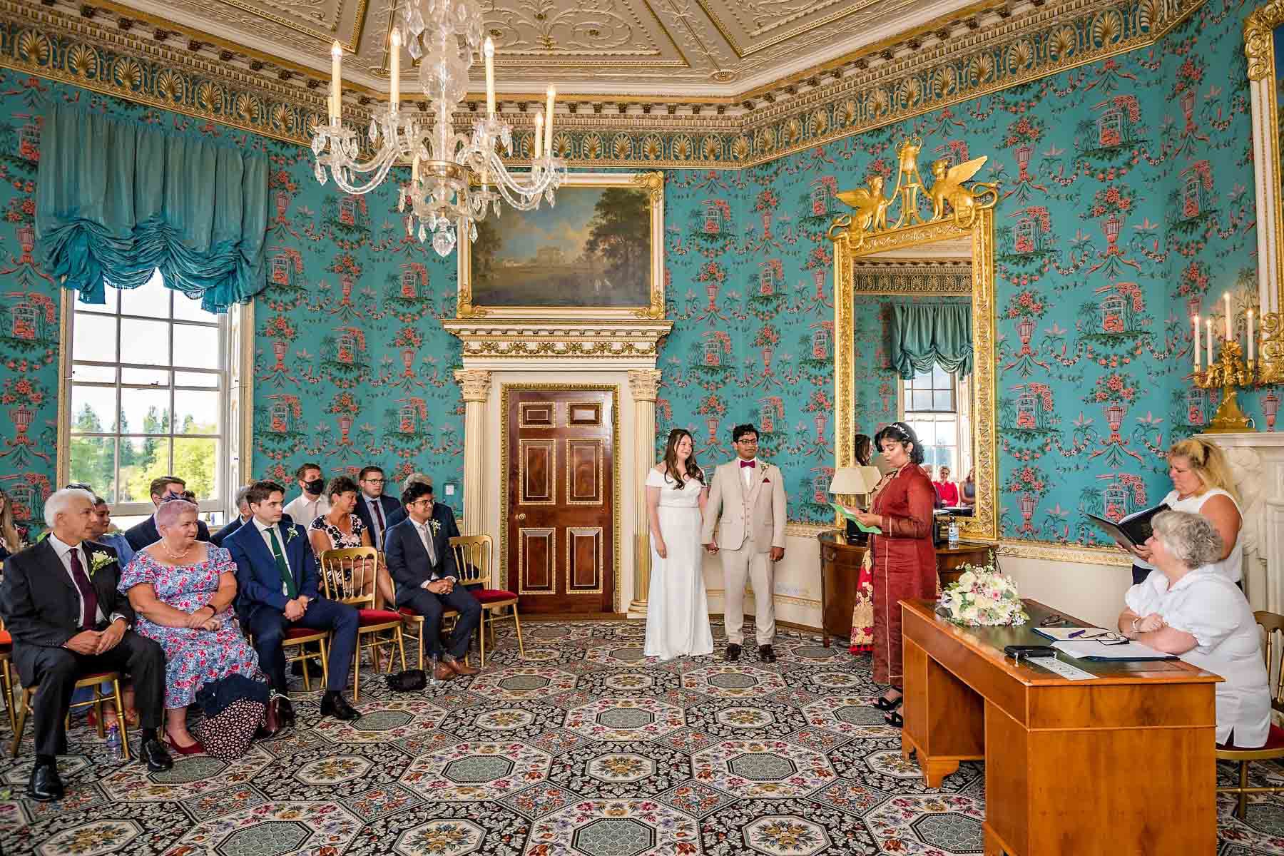 Wide shot showing a guest reading at wedding ceremony in Danson House's Salon