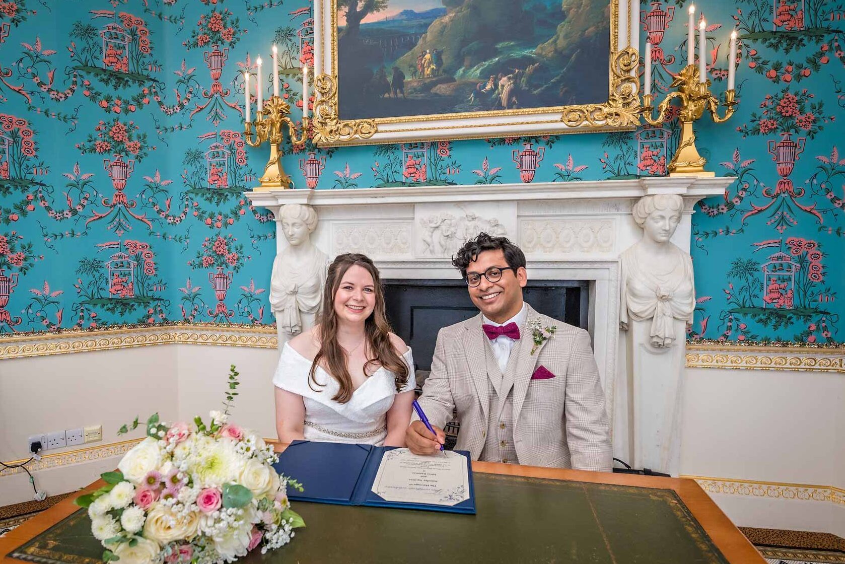 The happy newlyweds smiling with dummy register after their wedding ceremony in the Salon, Danson House