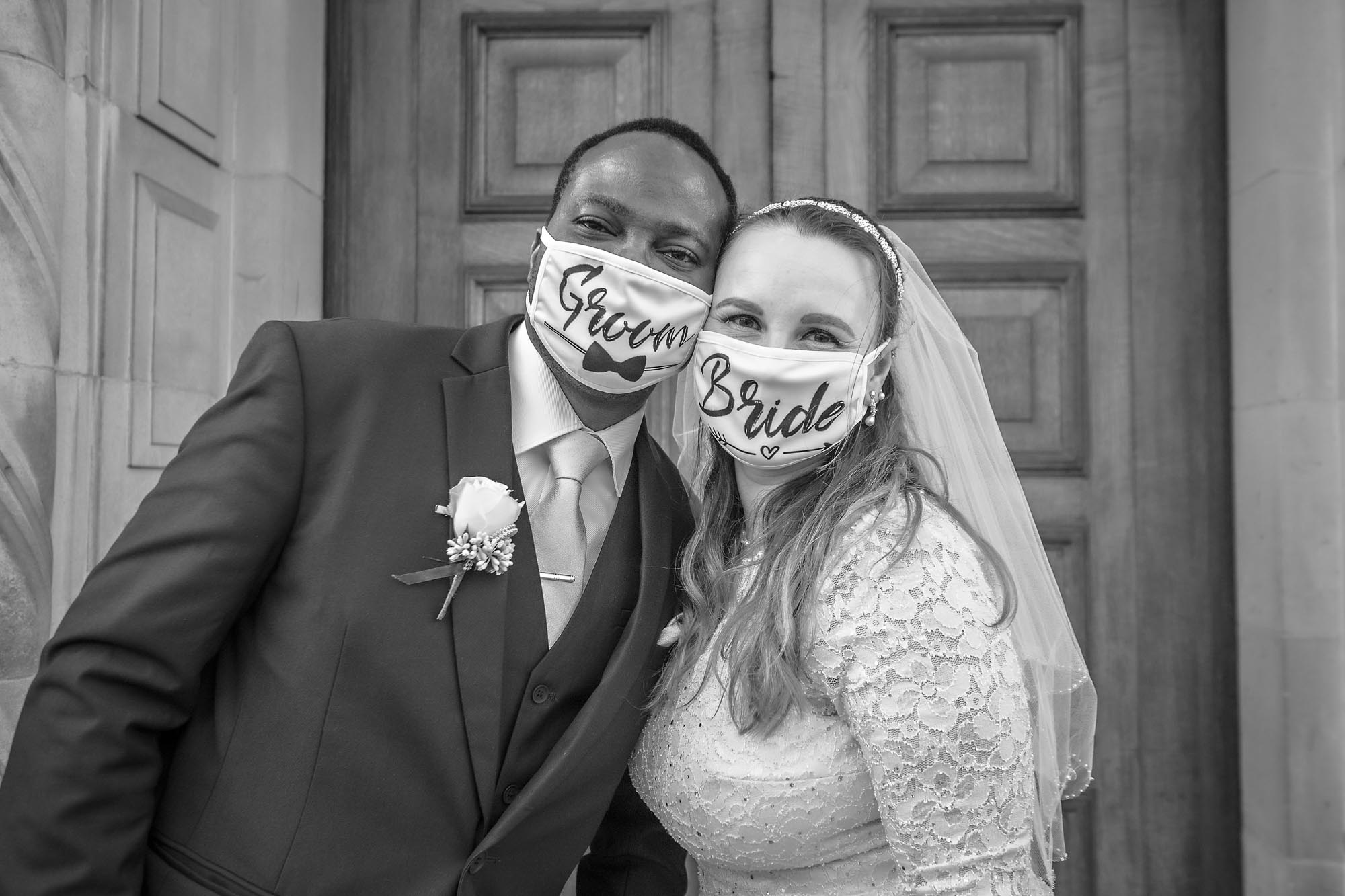 Wedding couple posing with 'Bride' and 'Groom' Covi-19 Masks outside Wandsworth Town Hall