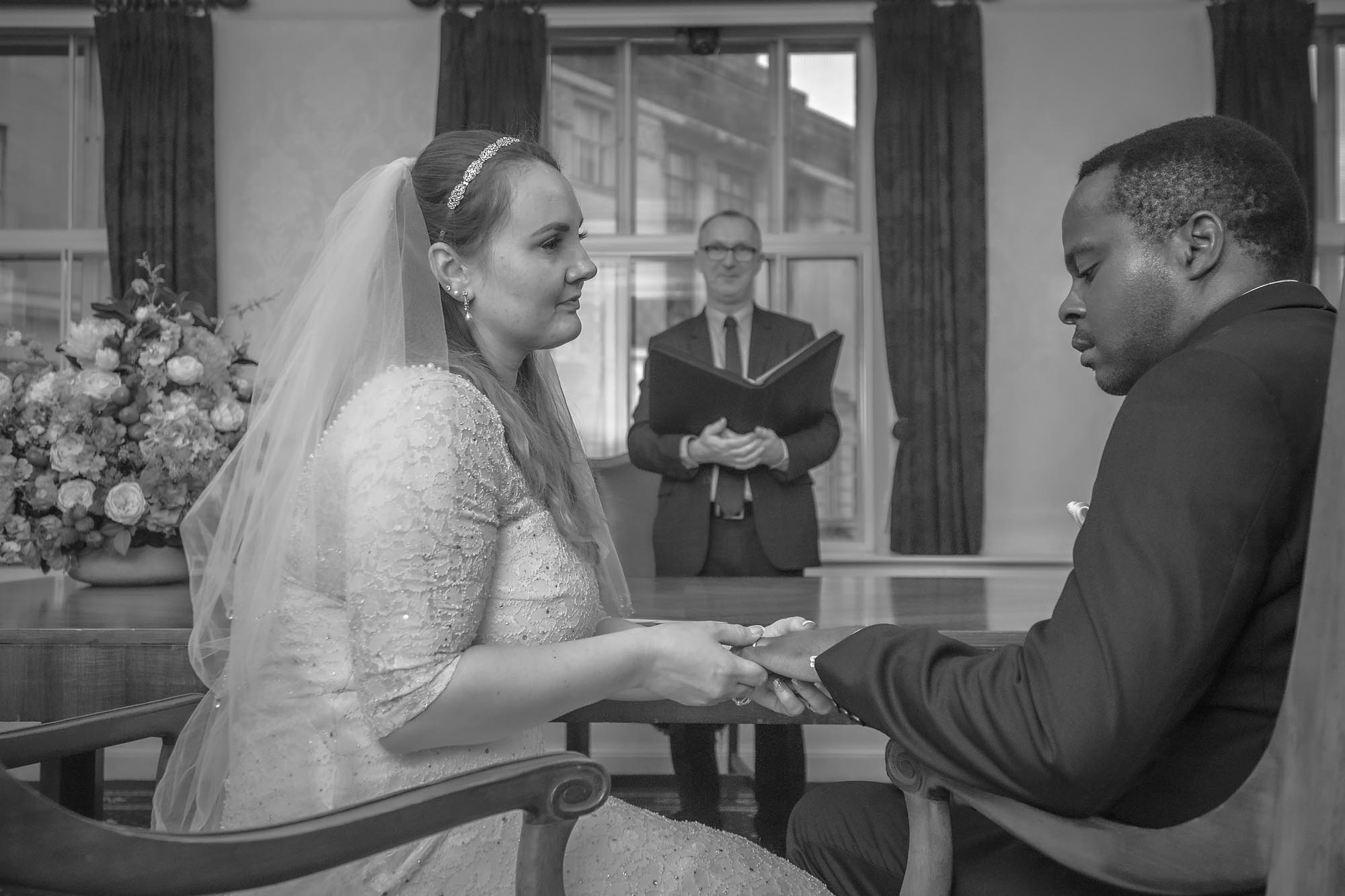 The bride places the ring on her groom's finger at their Wandsworth Town Hall wedding