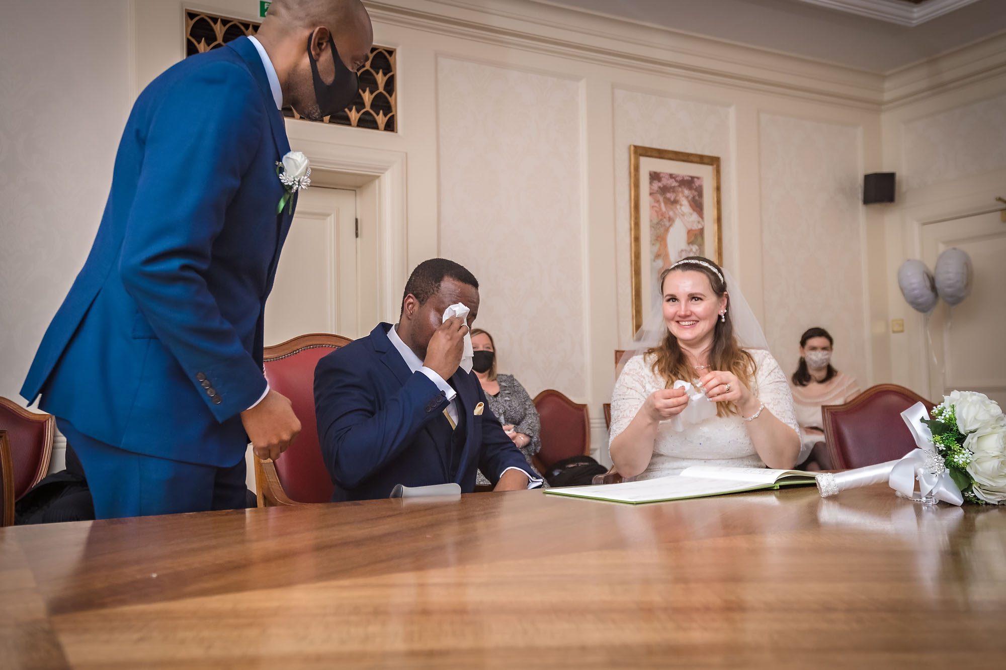 An emotional groom dabs his eyes at a South London wedding whilst the bride smiles at the camera