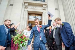 The groom punches the air as he leaves his Old Marylebone Town Hall wedding with his bride