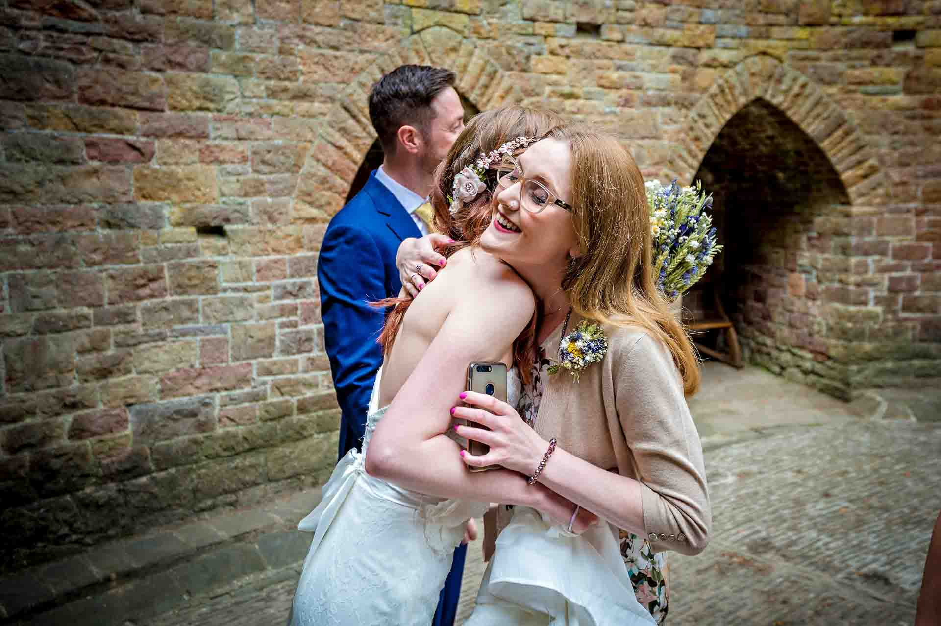 Bride's sister hugs her after wedding ceremony