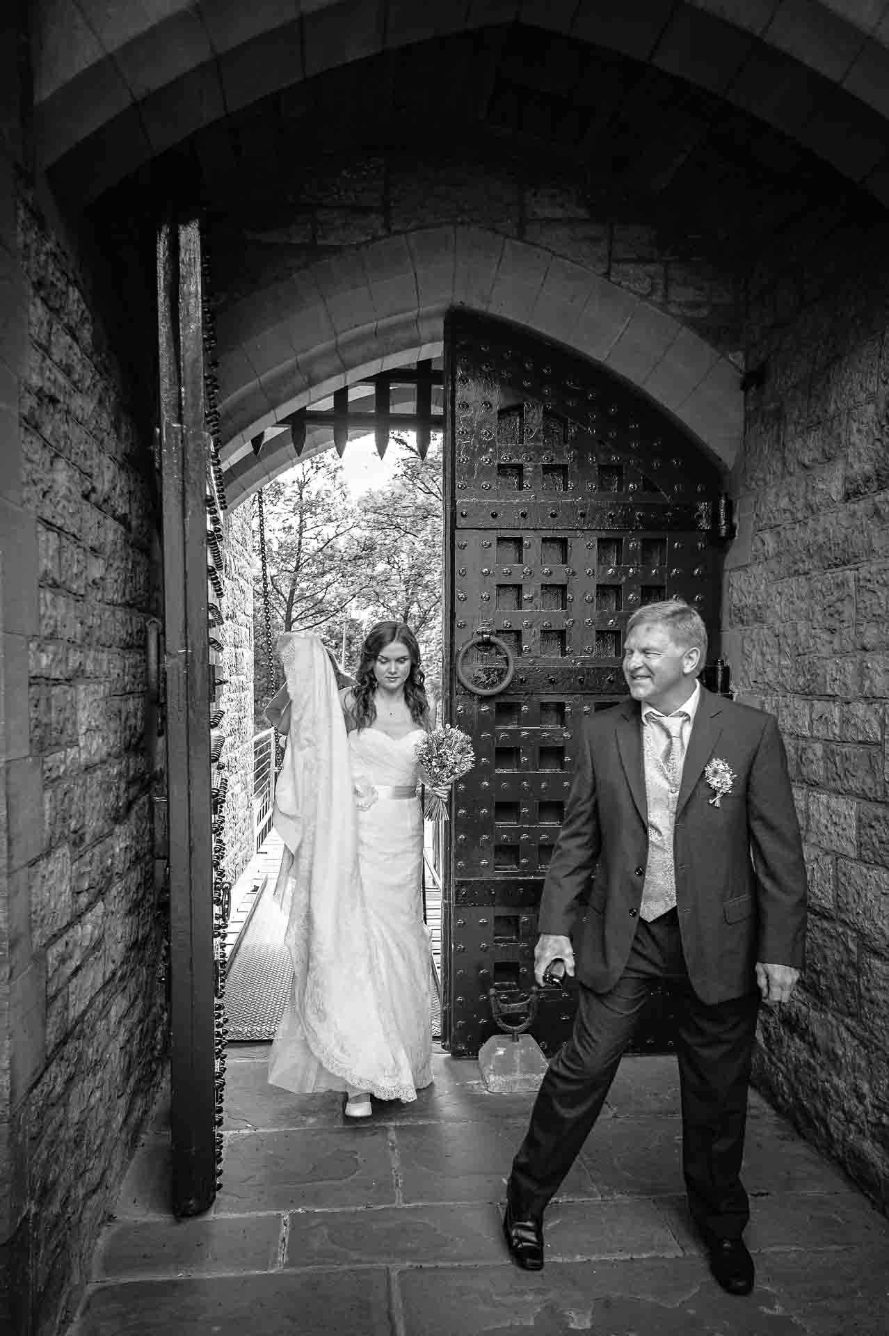 Castell Coch Wedding - Bride arrives through portcullis gate with step-father